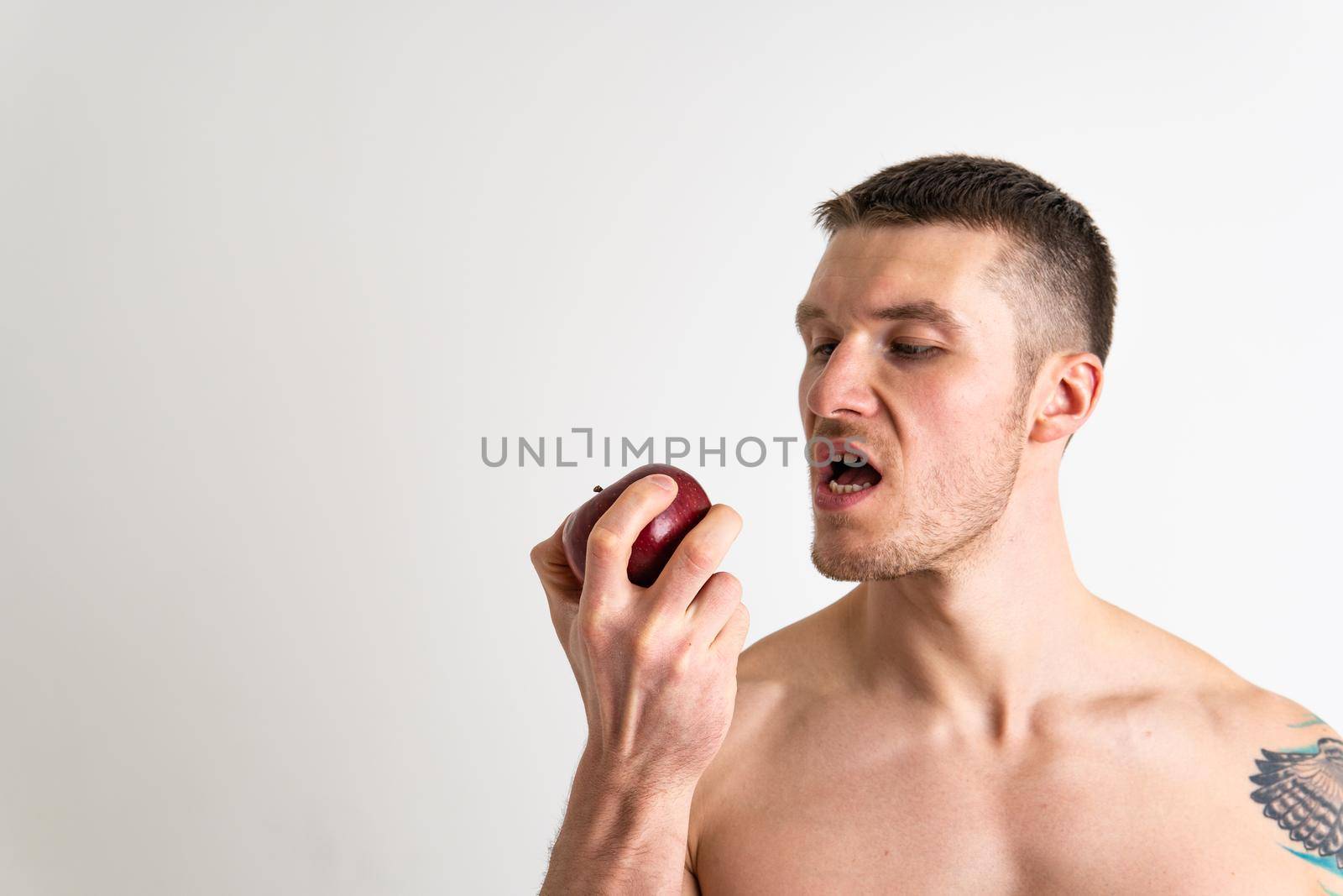 Man holds apples in fitness white background isolated apple man body, muscular food lifestyle person. strength bodybuilder chest