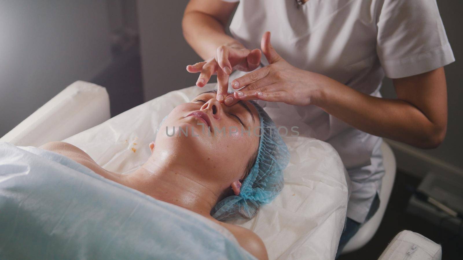 Woman doctor performes cosmetic procedure - mask facial massage at spa salon skincare, close up