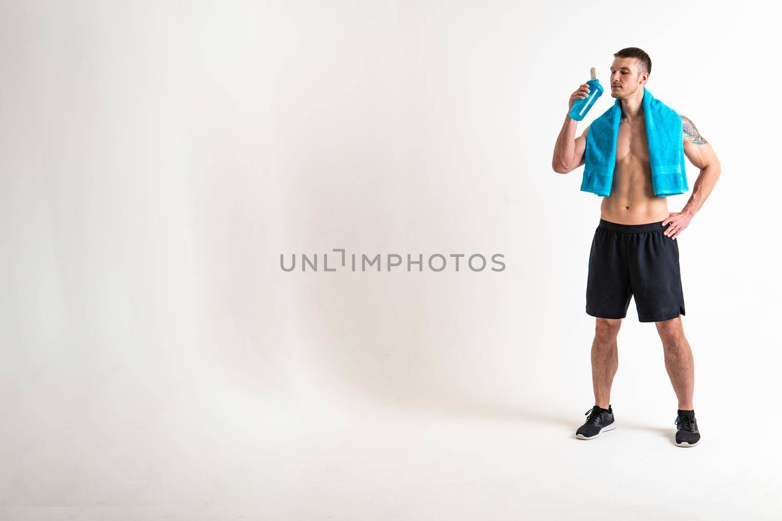 Male drink-water fitness is pumped with a towel on a white background isolated strong athlete energy bottle break athletic. Towel power pace, caucasian one muscle