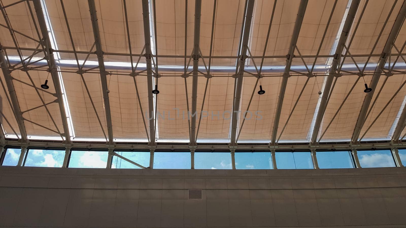 Curved roof with windows of a large shopping center indoors. Modern metal and glass ceiling construction