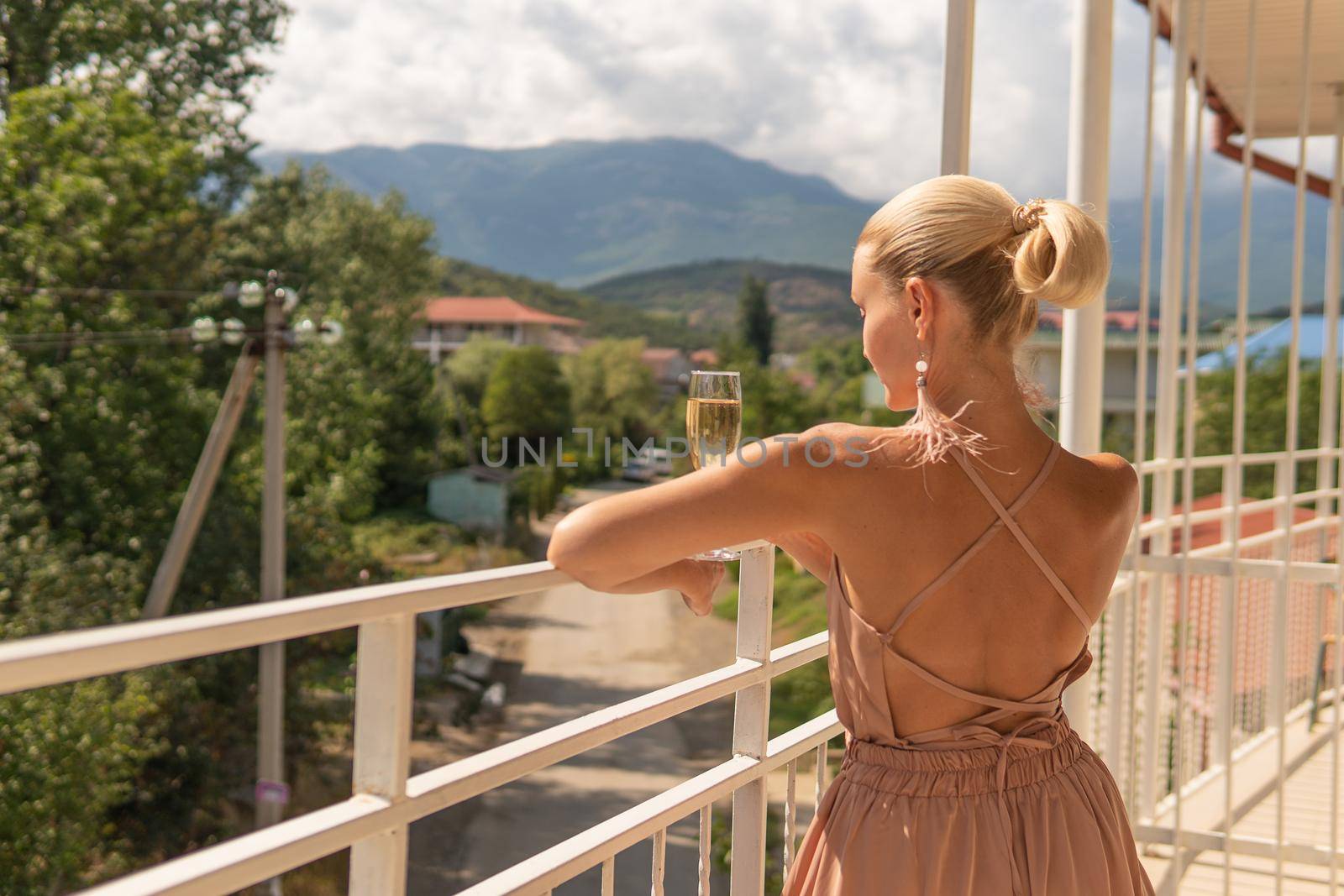 Girl stands with champagne on the mountain balcony of life, portrait enjoy life outdoors, rest at home. sky holiday, resort