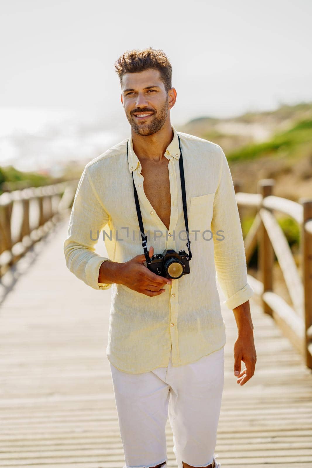 Smiling man photographing in a coastal area with an SLR camera
