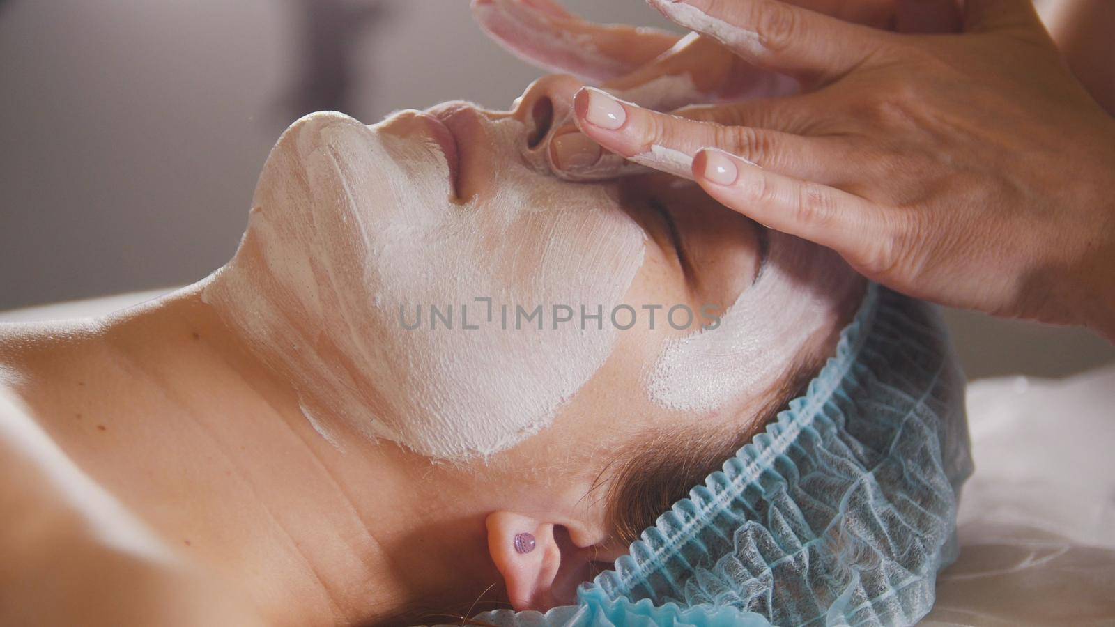 Female doctor performes cosmetic procedure - mask facial massage at spa salon skincare, close up