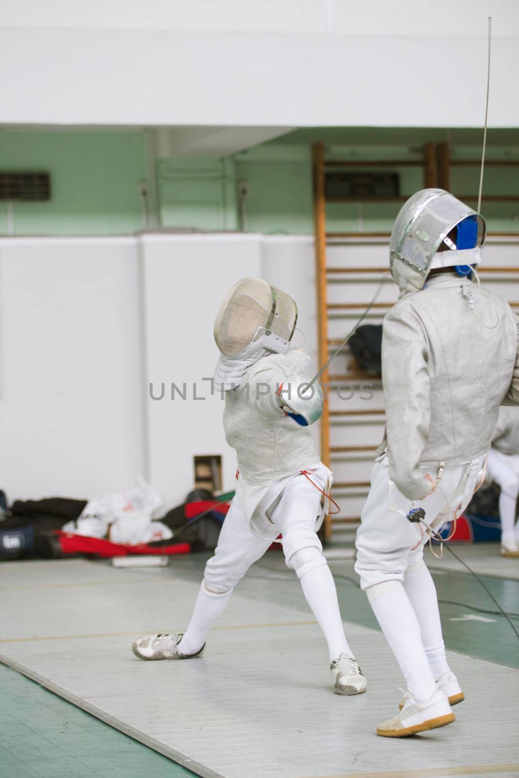 Two young fencers fighting on the fencing competition by Studia72