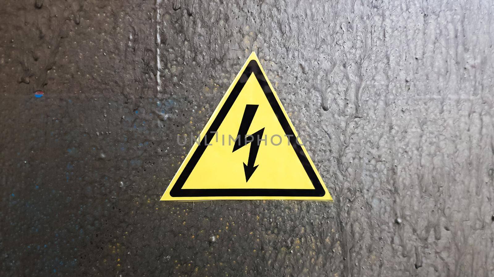 safety sign yellow and black on a silver metal background. High voltage lightning in a triangle caution caution danger electricity death