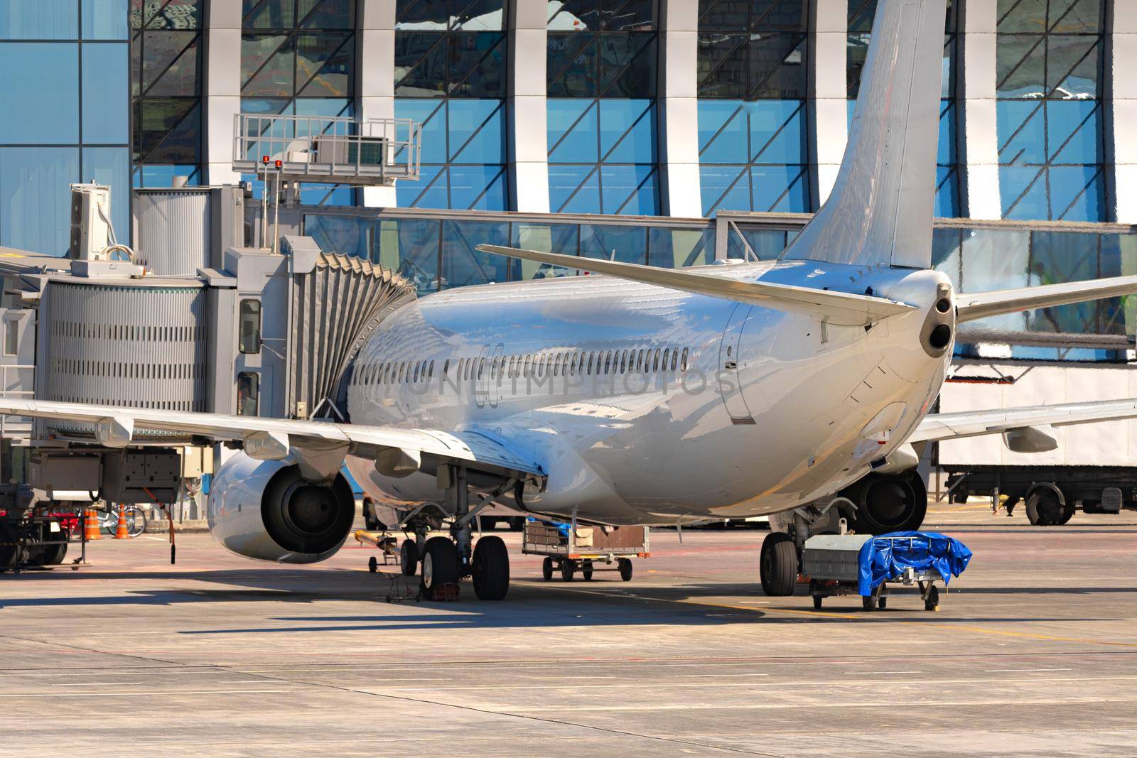 Airplane is parked near gate of airport terminal on sunny day