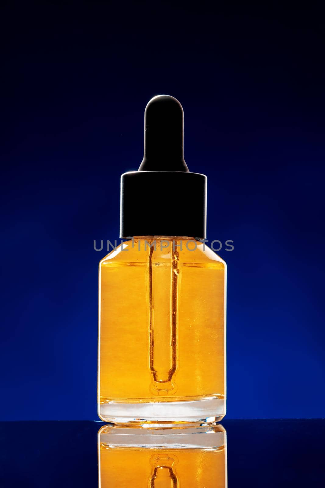 Glass bottle with cosmetic oil on dark background close up