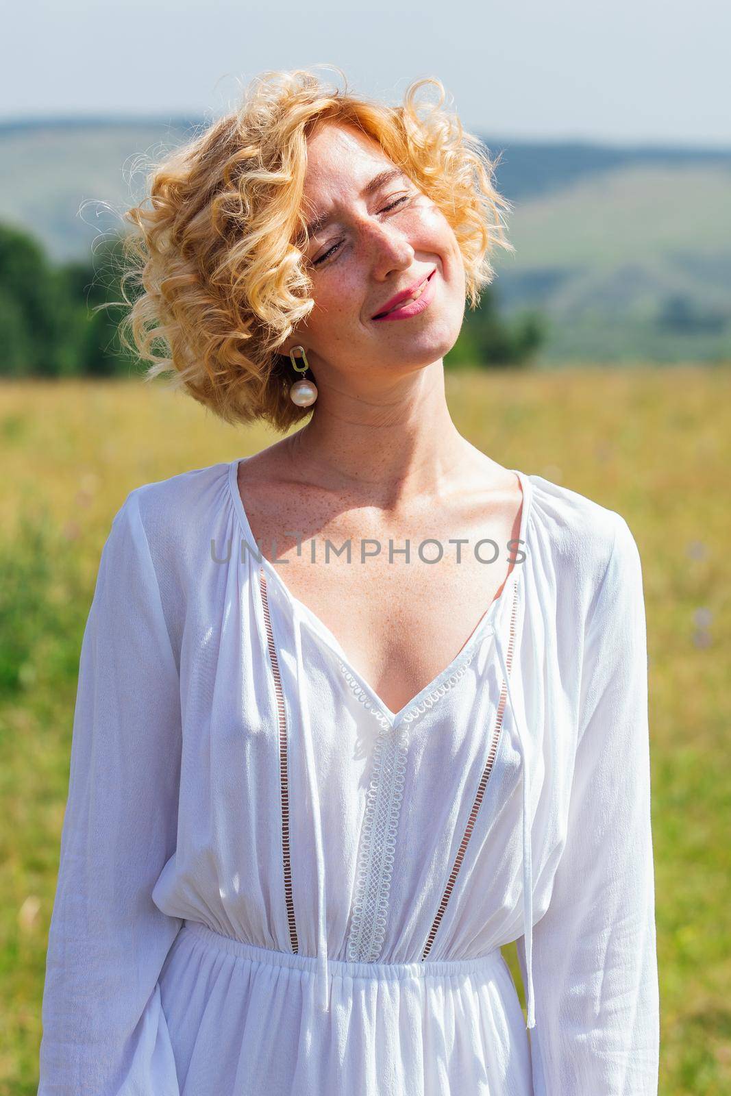 Beautiful blonde woman with short curly hair outdoors. by Smile19