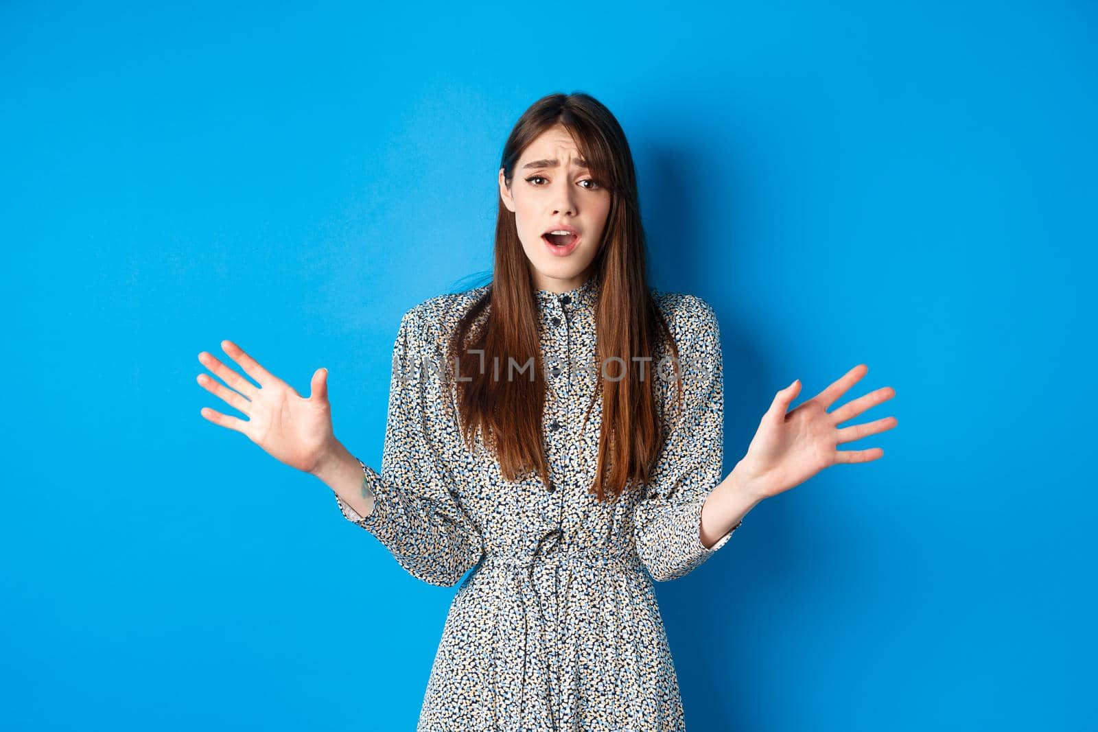 Sad and gloomy woman in dress facing failure, looking distressed and sighing upset, losing and standing on blue background.