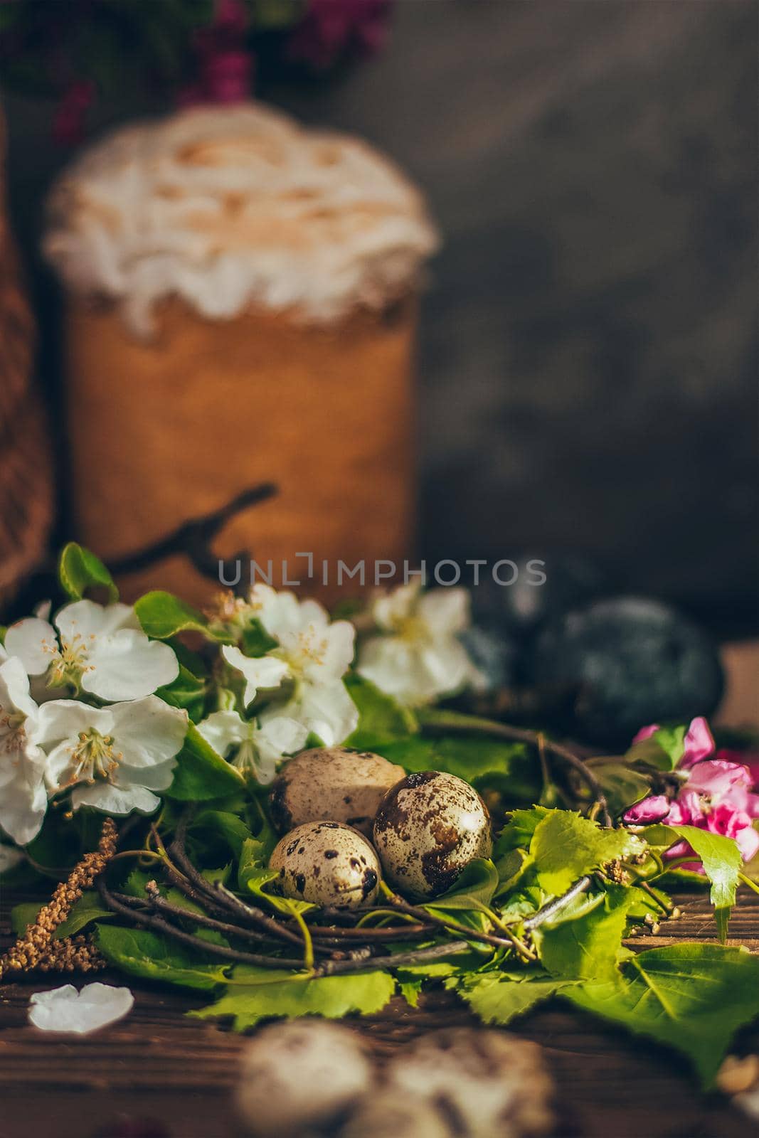 Easter eggs in the nest on rustic wooden background with apple blossom branch