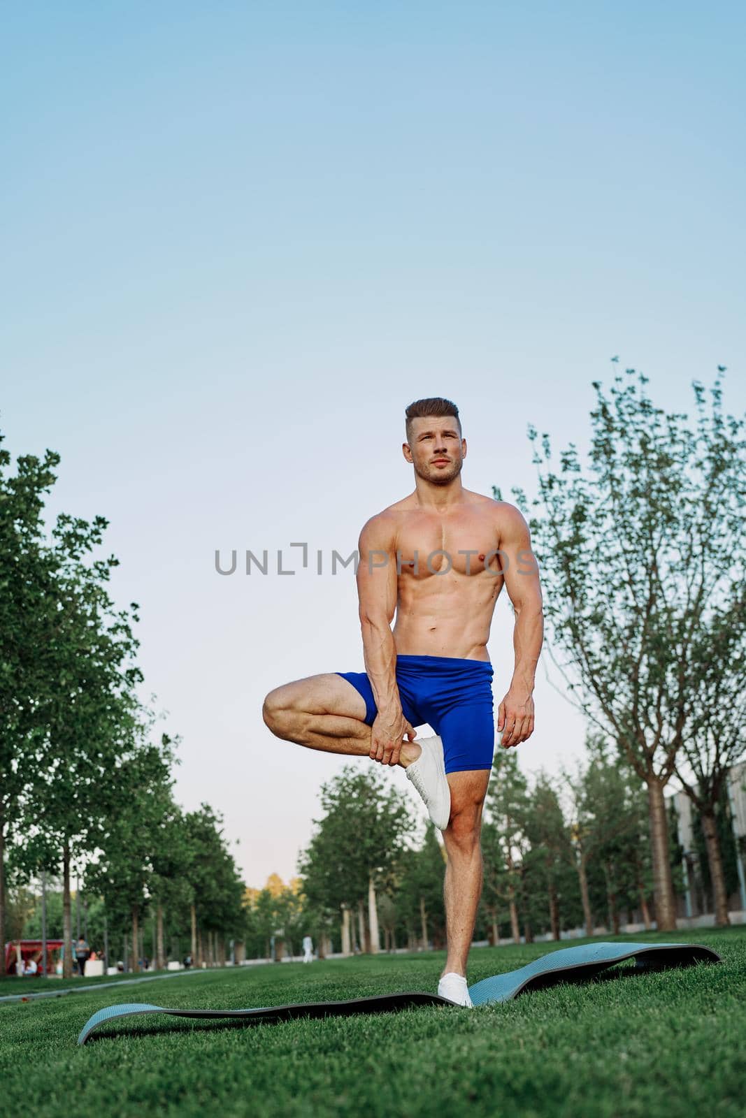 athletic man in blue shorts working out in the park. High quality photo