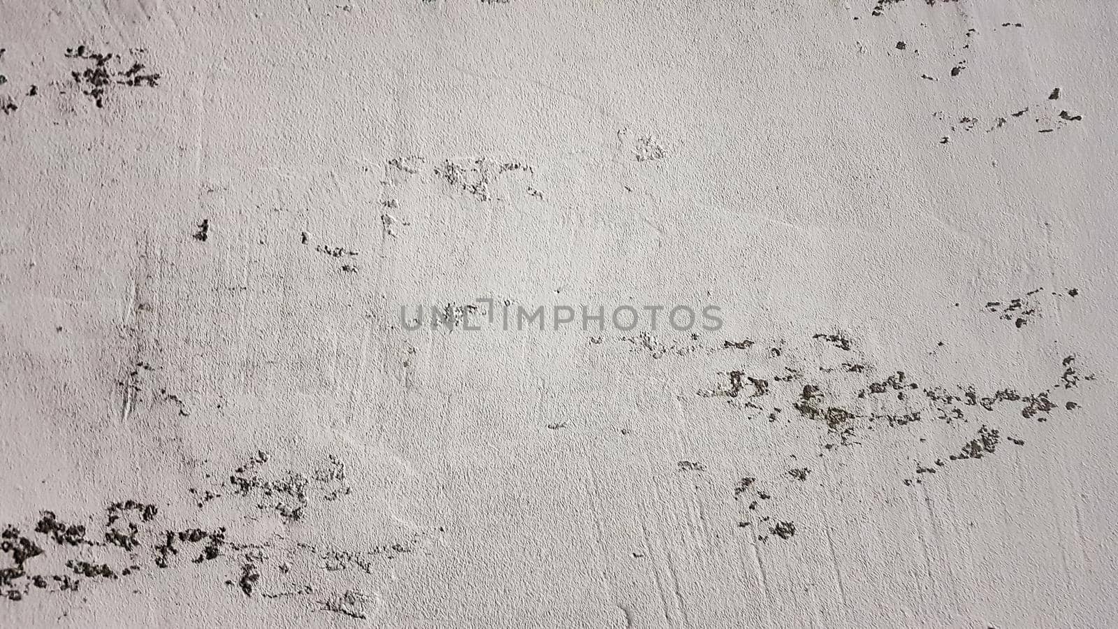 old shabby wall with cracks and chips with whitewash and exfoliated plaster, putty. Vintage gray textured putty on the wall. Rough grunge wall background