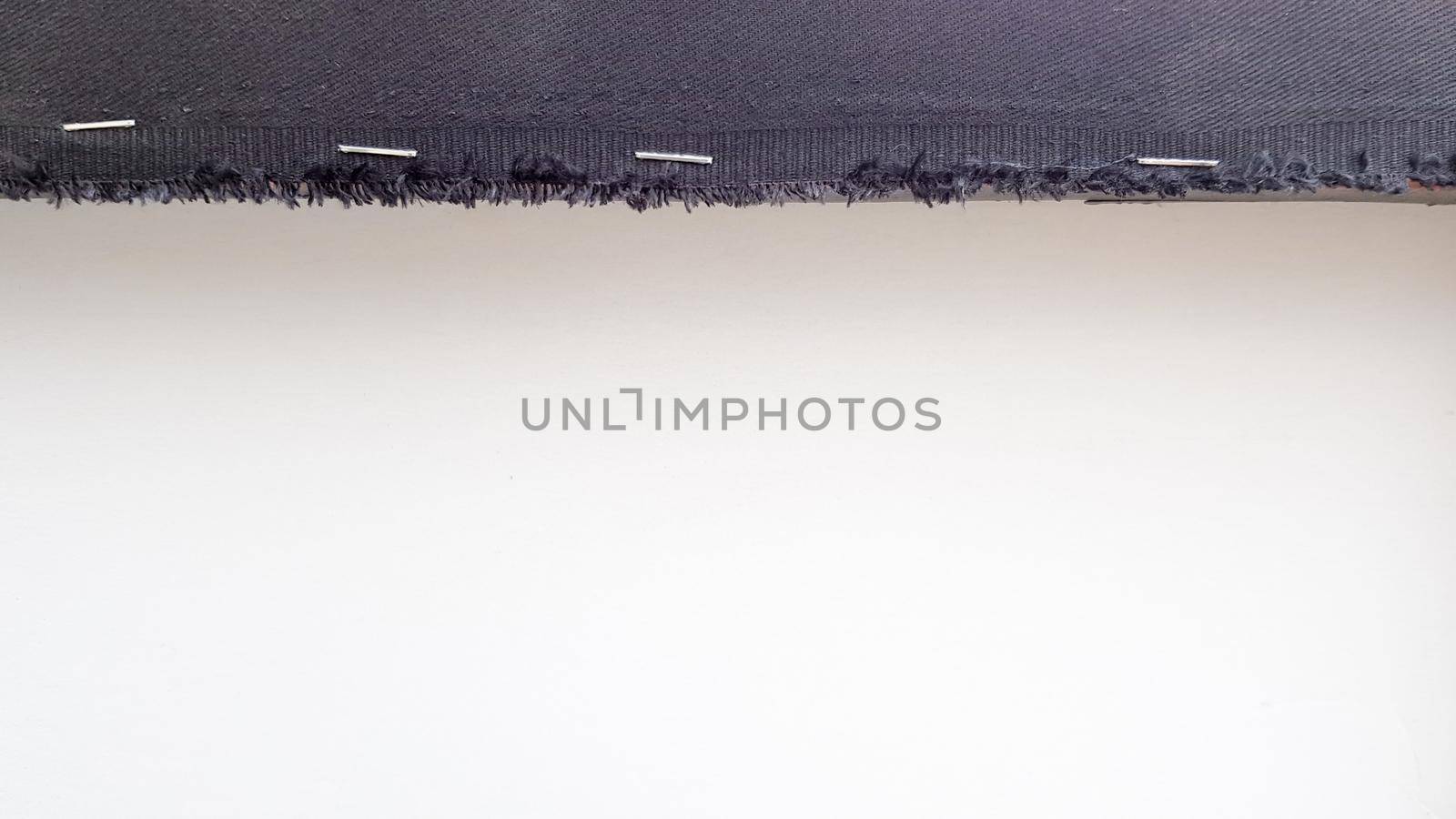 White background with a black fabric stripe punched with staples to a wooden plank. Abstract background with copy space