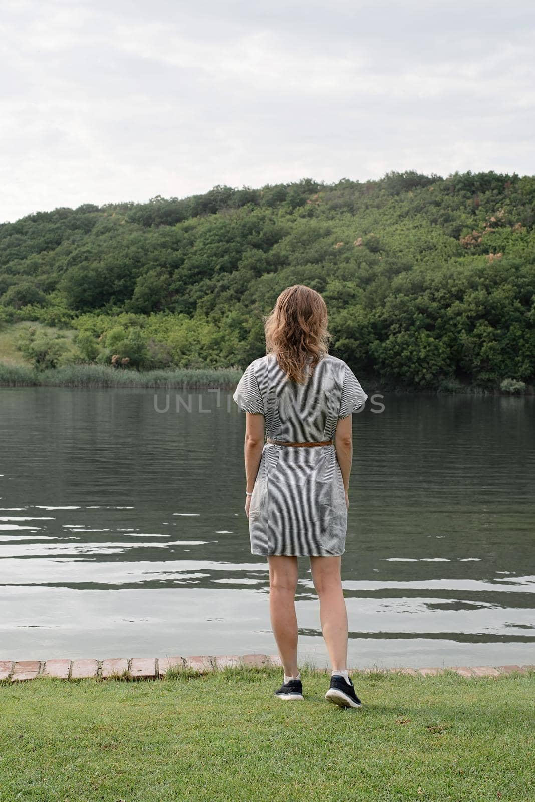 Back view of a woman standing near the lake by Desperada