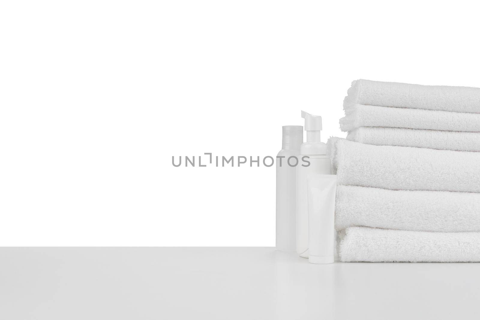 Composition of cosmetic bottles and towels isolated on white background