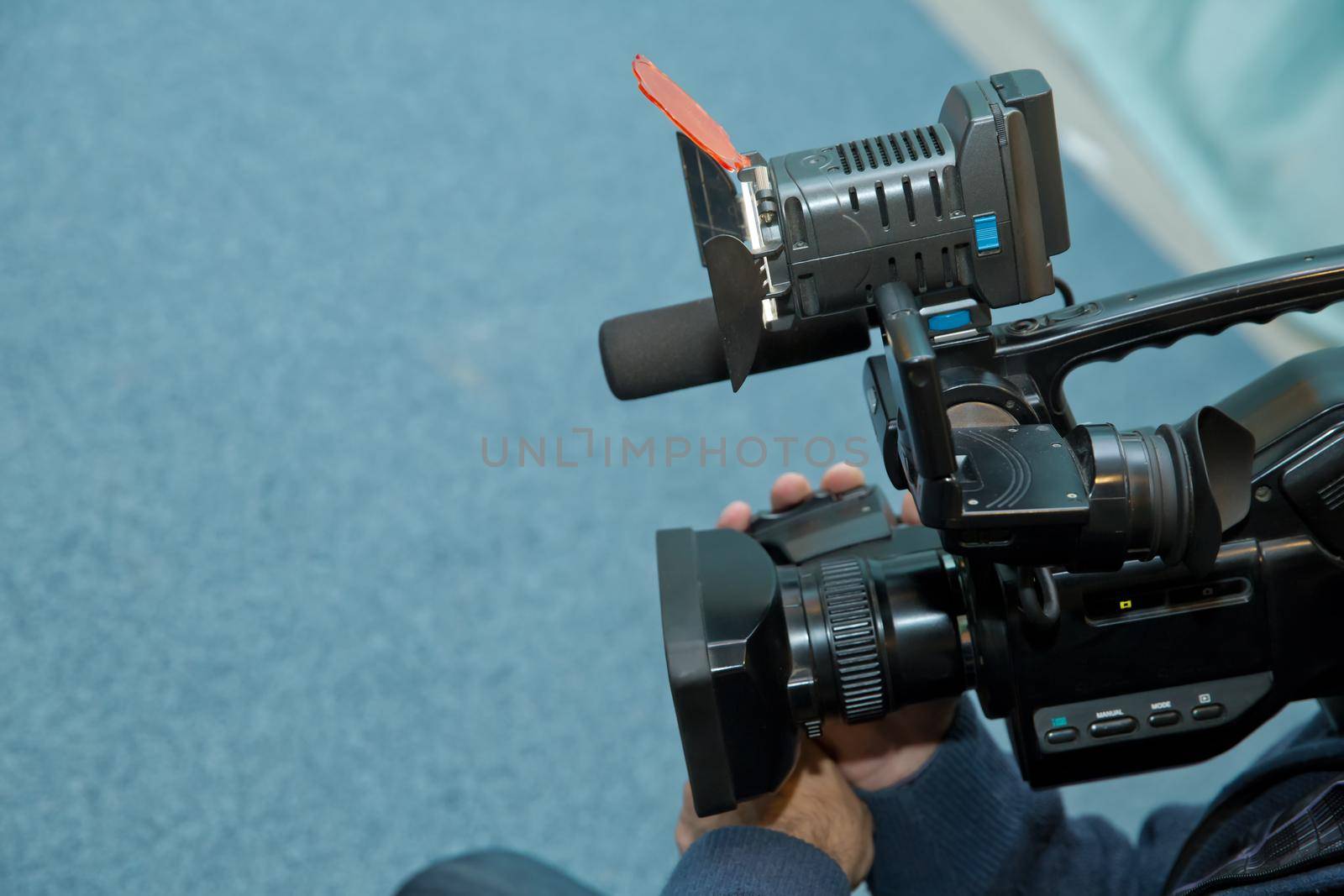 Covering an event with a video camera., Videographer takes video camera with free copy space for text., Video camera operator working with his equipment., close up of television operator with camera. by Adil_Celebiyev_Stok_Photo