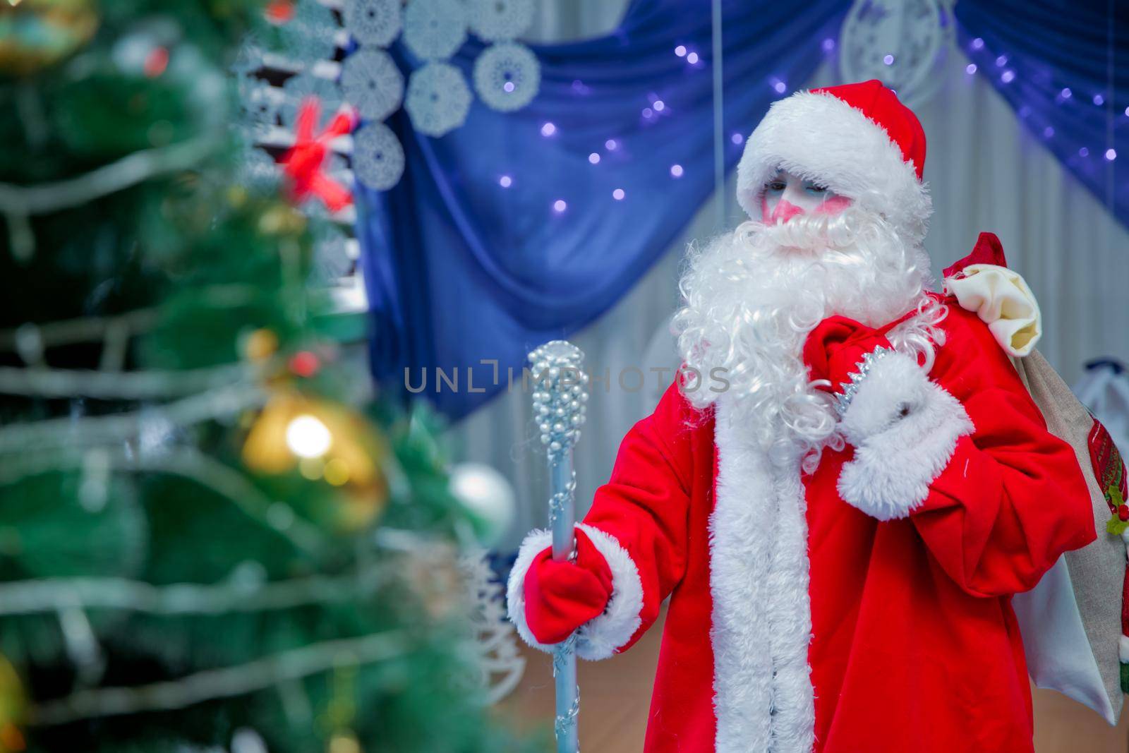 Father Frost speaks with a microphone . Santa Claus is singing Christmas songs against . Man in Santa Claus suit posing with microphone. by Adil_Celebiyev_Stok_Photo