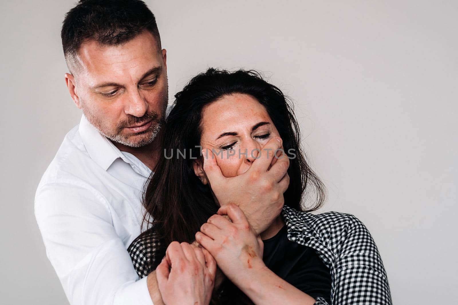 An aggressive man covers the mouth of a beaten woman so that she cannot scream. Domestic violence by Lobachad
