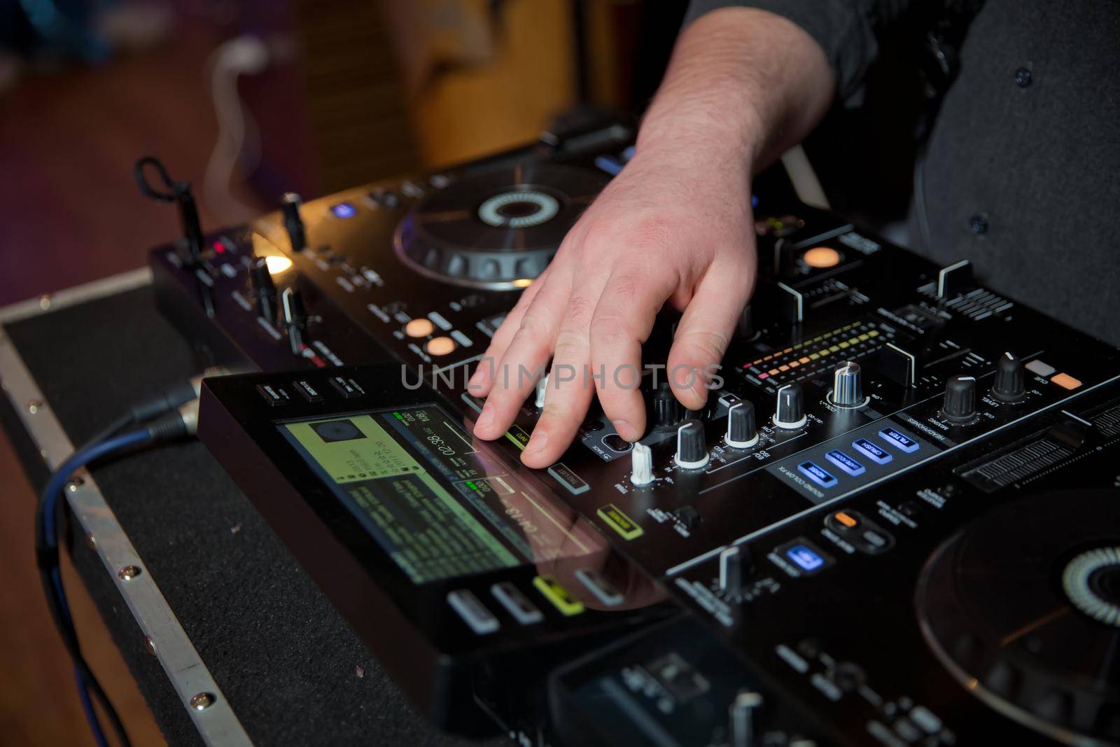 Men's hands press the buttons on the DJ remote, it makes music . DJ's hands at the music mixer at a party - playing some fine songs for the guests color toned image