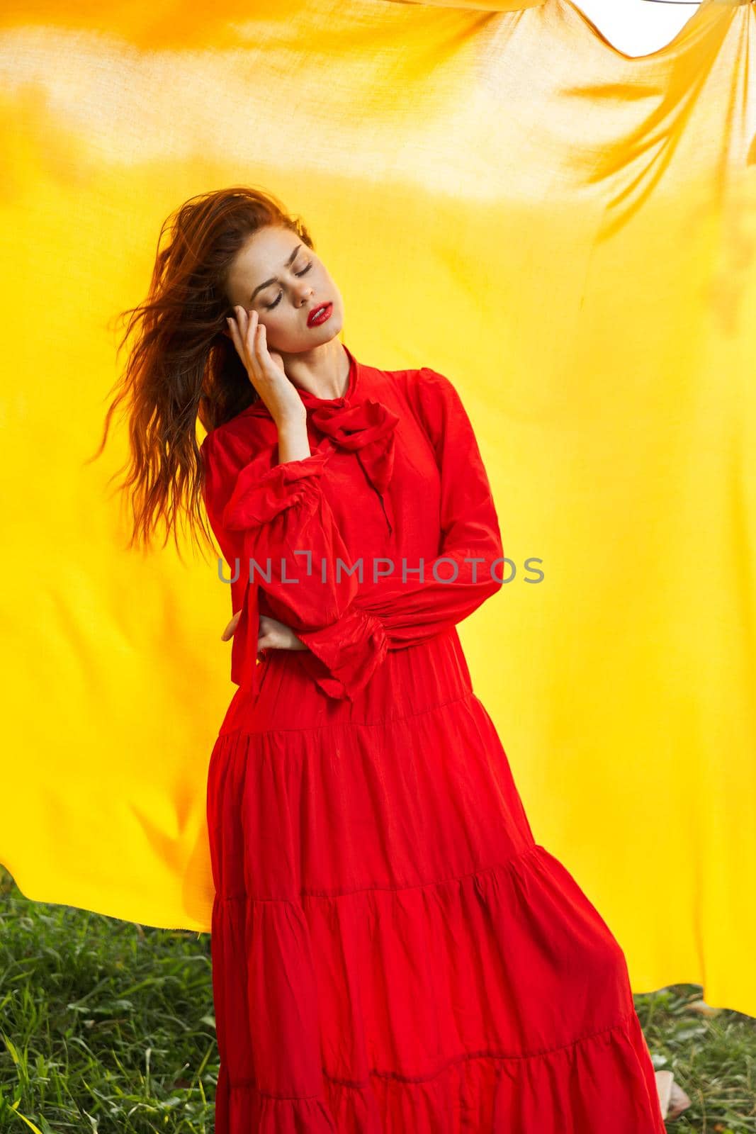 pretty woman in red dress yellow fabric on nature background. High quality photo