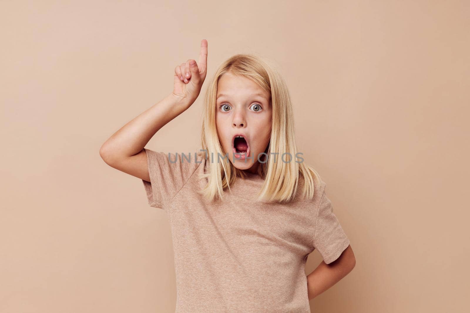 Positive little girl in a beige t-shirt isolated background. High quality photo