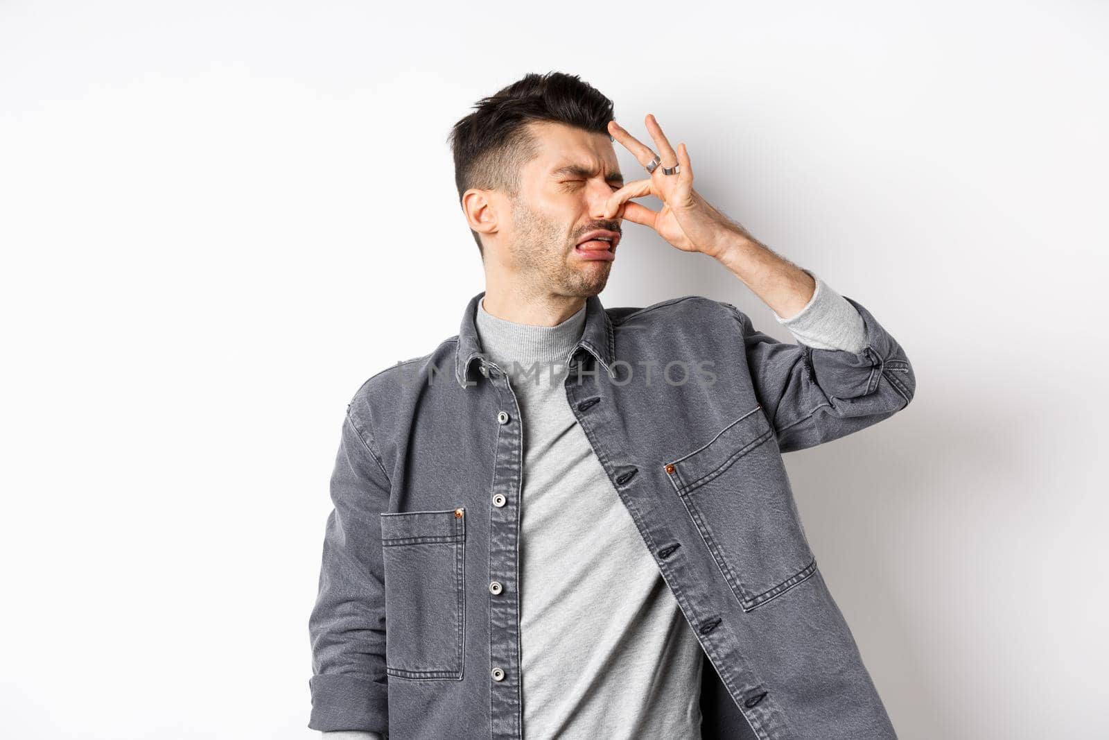 Disgusted man turn away and shut nose from bad smell, disgusting reek, standing on white background by Benzoix