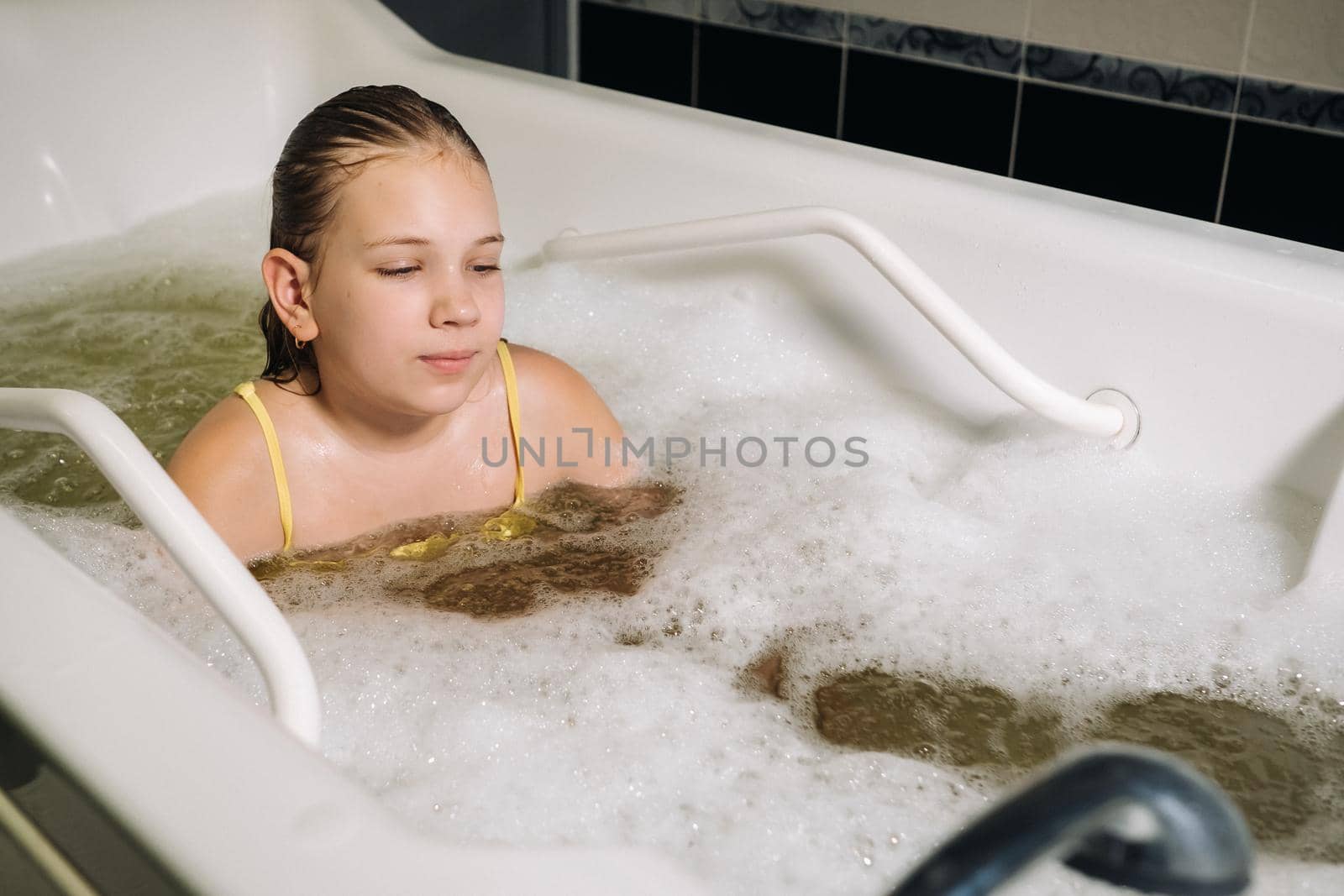 a little girl takes the procedure in a mineral bath. The patient receives water treatments with a mineral pearl bath by Lobachad