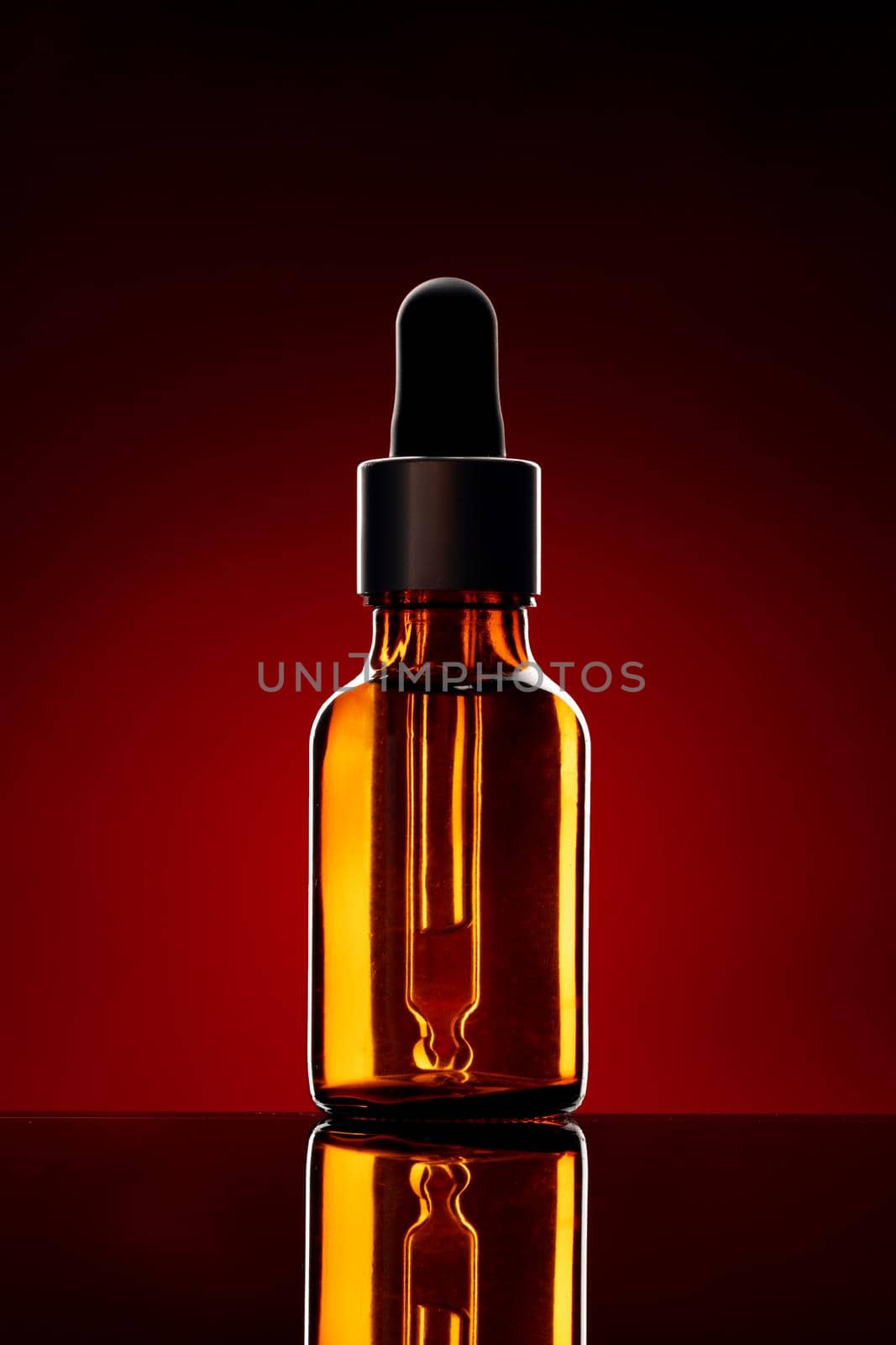 Glass bottle with cosmetic oil on dark background close up