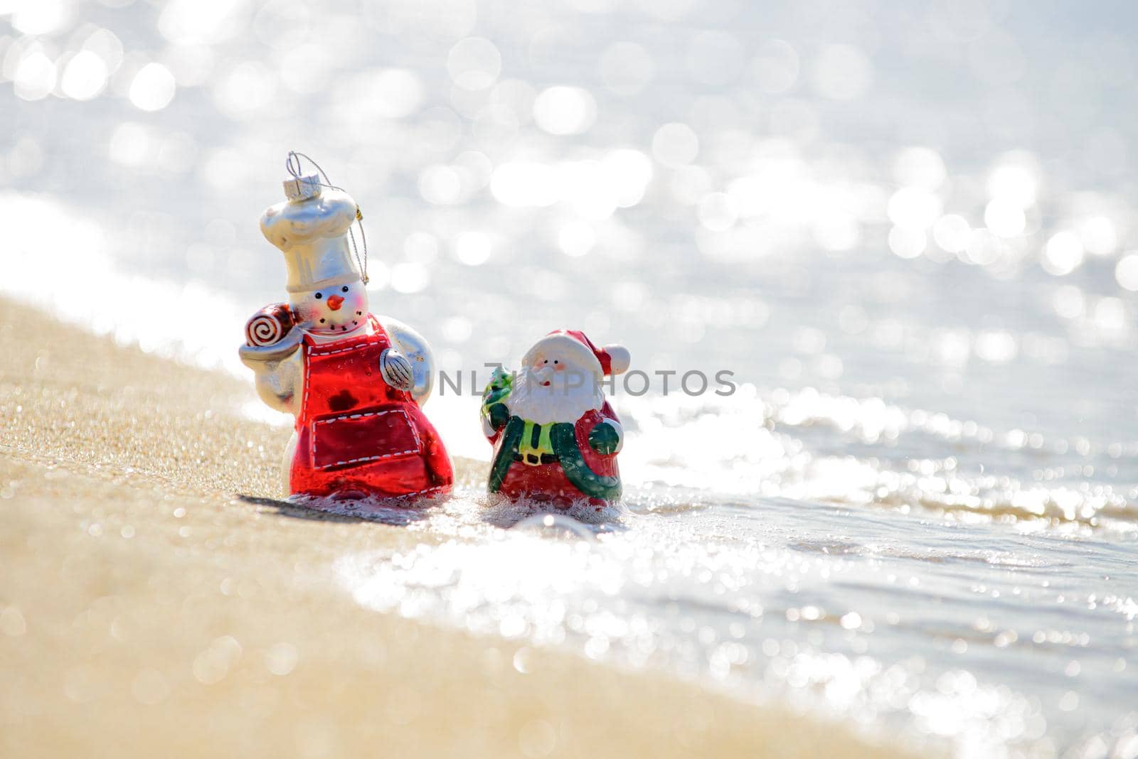 Snowman and santa claus on sea beach. Christmas and New Year's vacation in hot countries