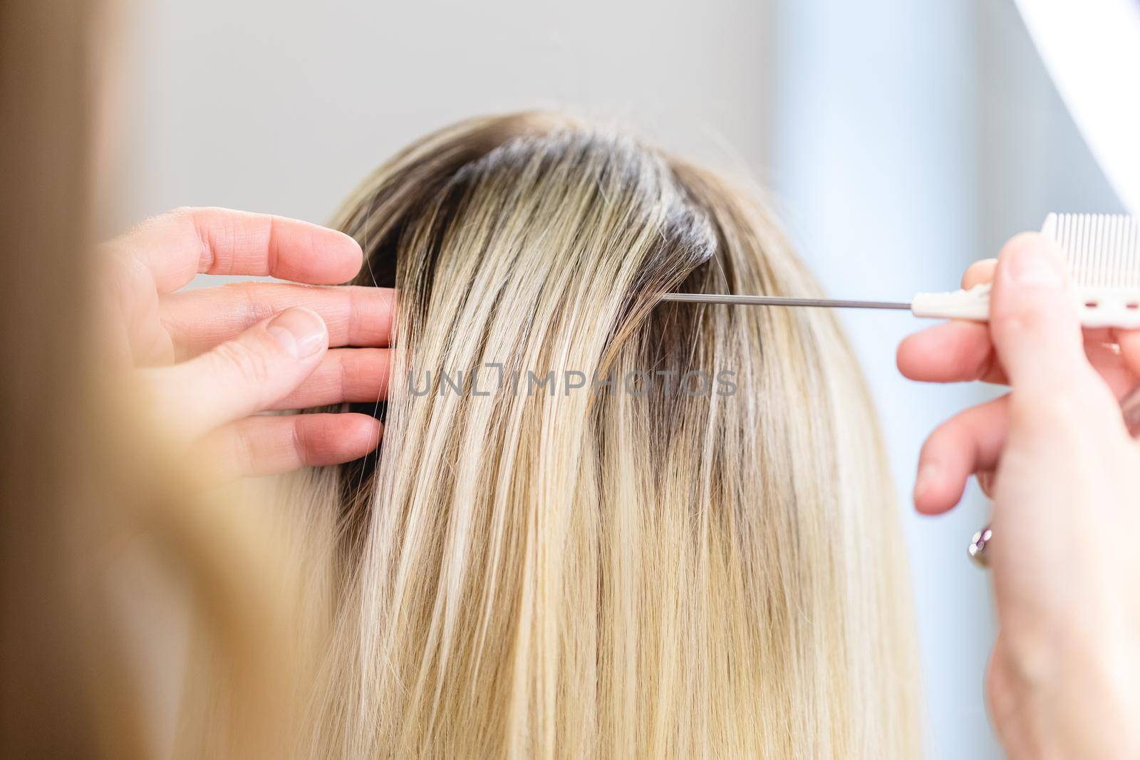 Blonde woman getting a new hairstyle by hairdresser at beauty salon