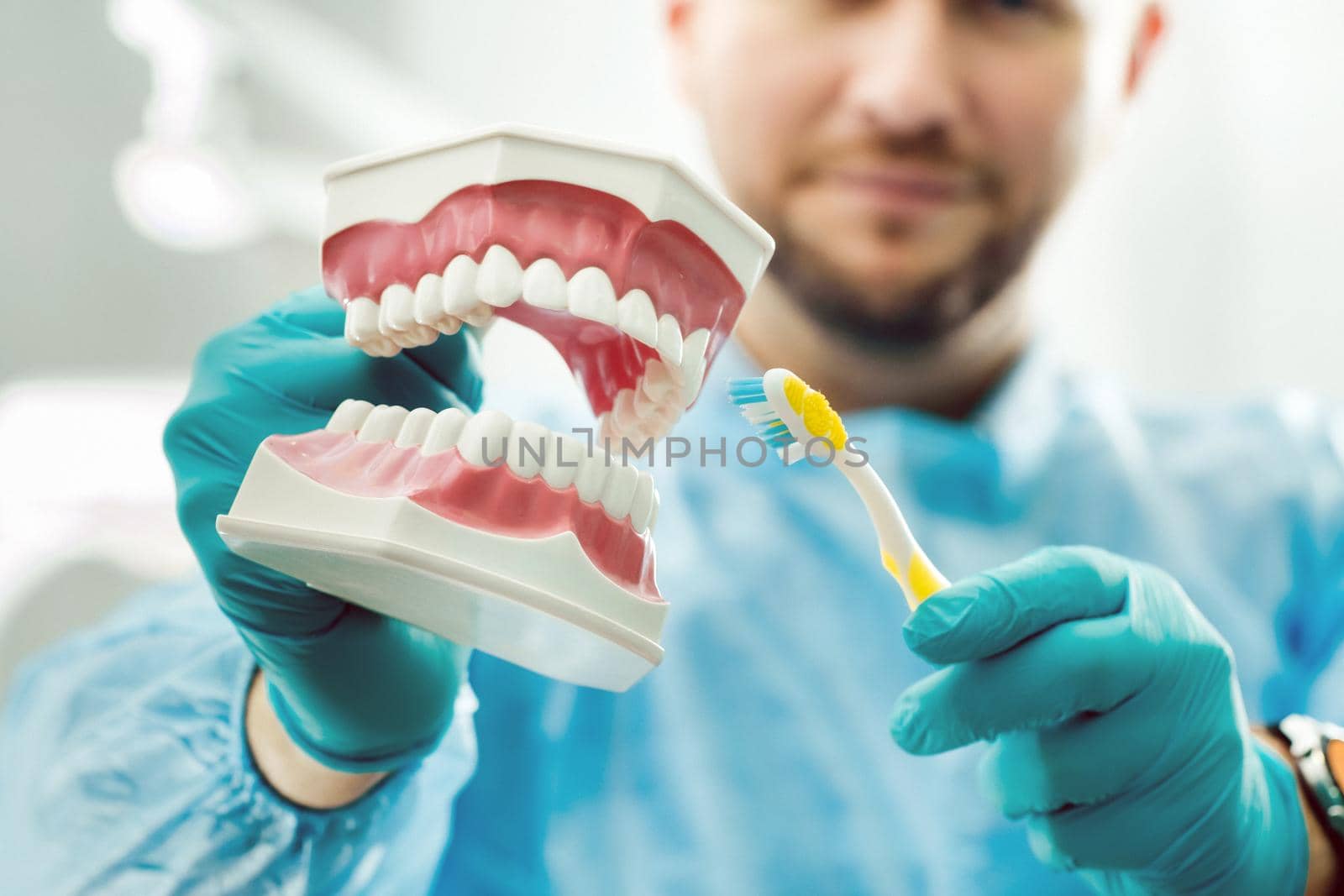 A model of a human jaw with teeth and a toothbrush in the dentist's hand by Lobachad