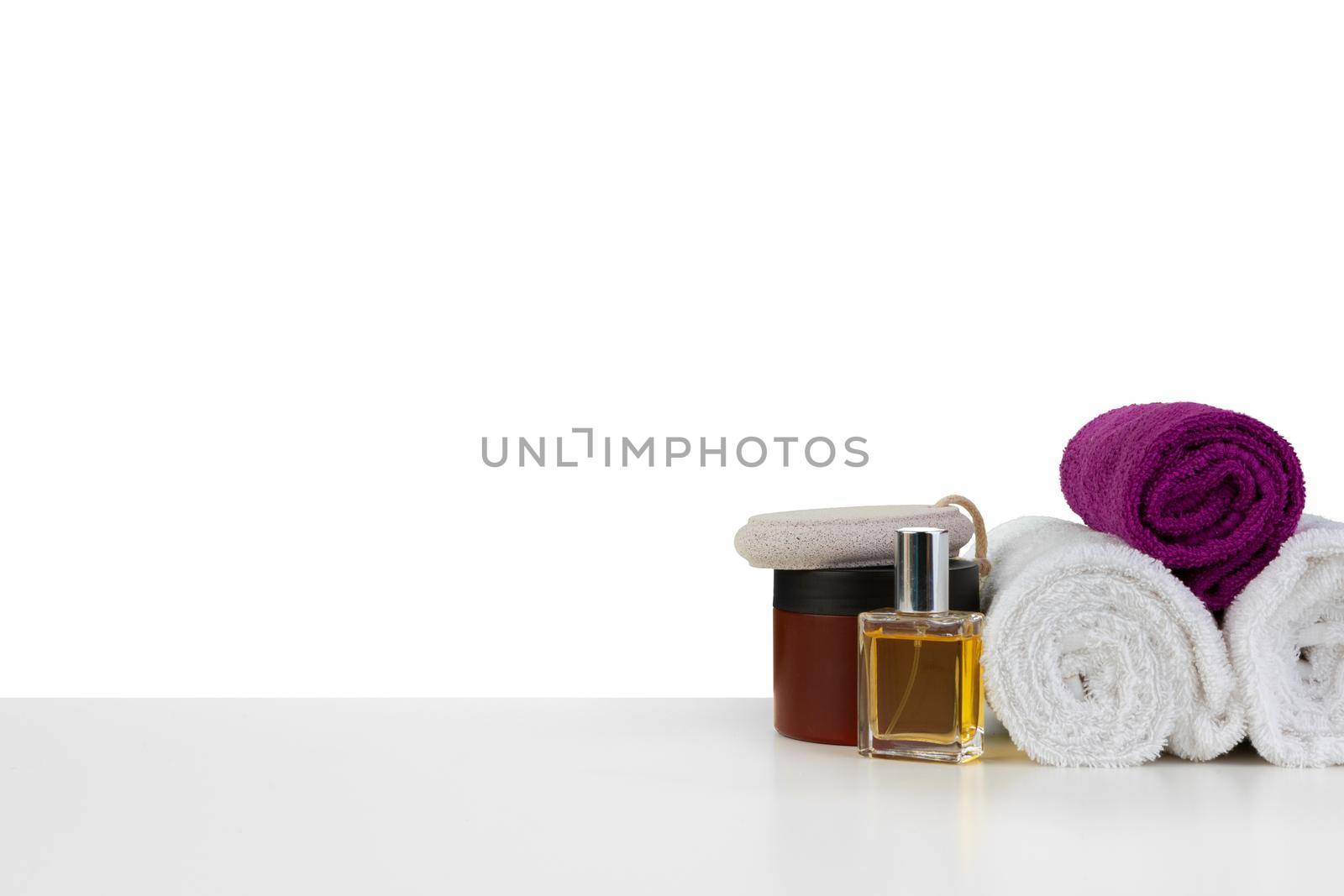 White towels and spa skincare cosmetics on white background, front view