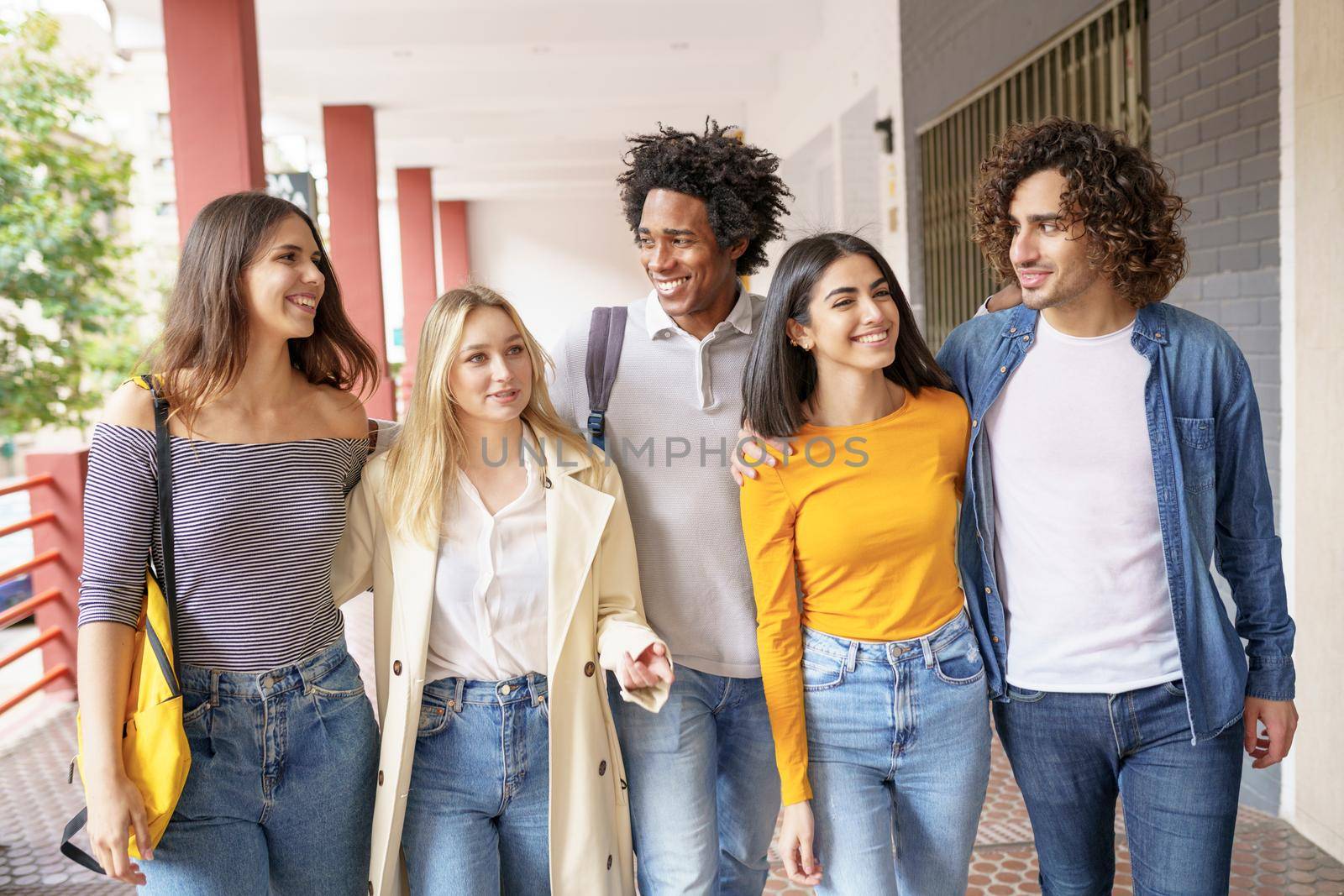 Multi-ethnic group of friends walking together on the street while chatting and having fun.