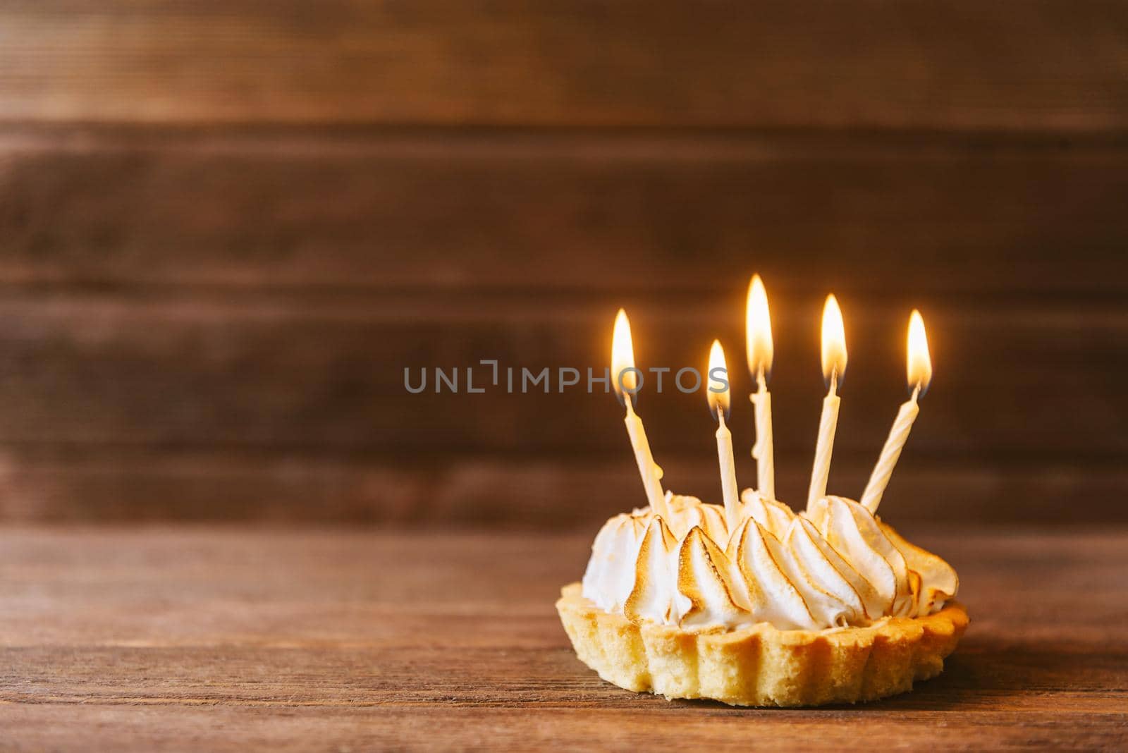 Birthday cake with five candles on a wooden background. Copy-space in left part of image.