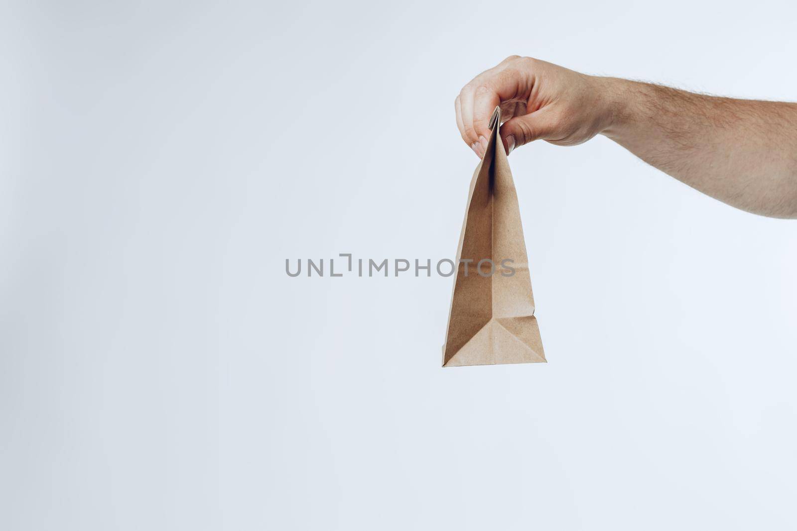 Courier hands giving packed food delivery close up against grey background