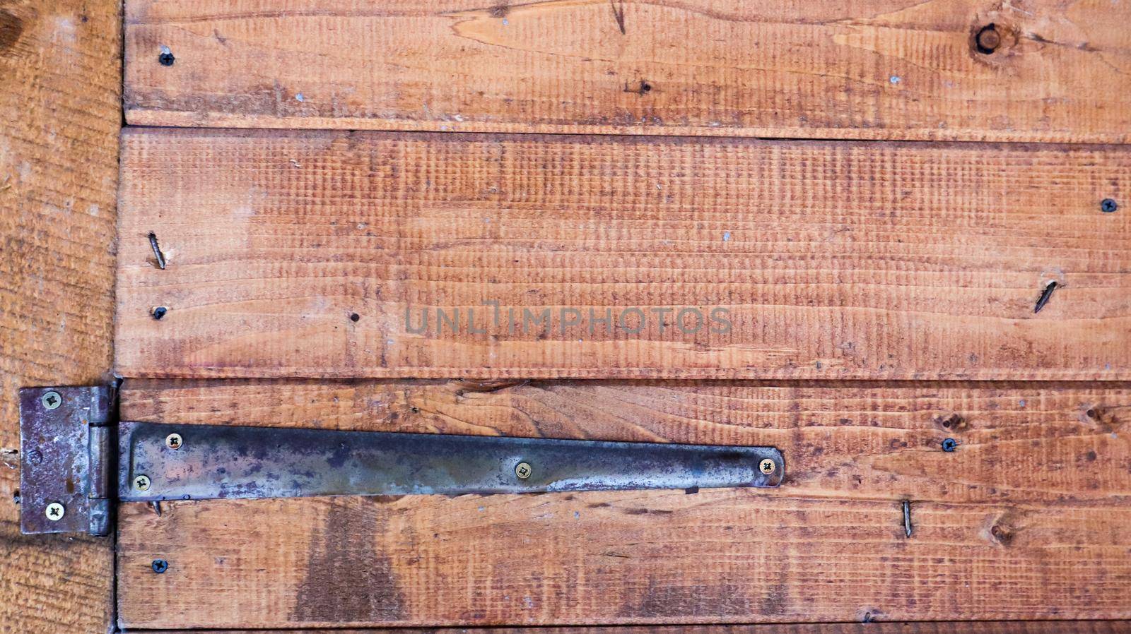 Old wooden background with a rusty hinge. Antique door hinges. Black metal on brown wood close up detailed view. Vintage door hinge close up door background