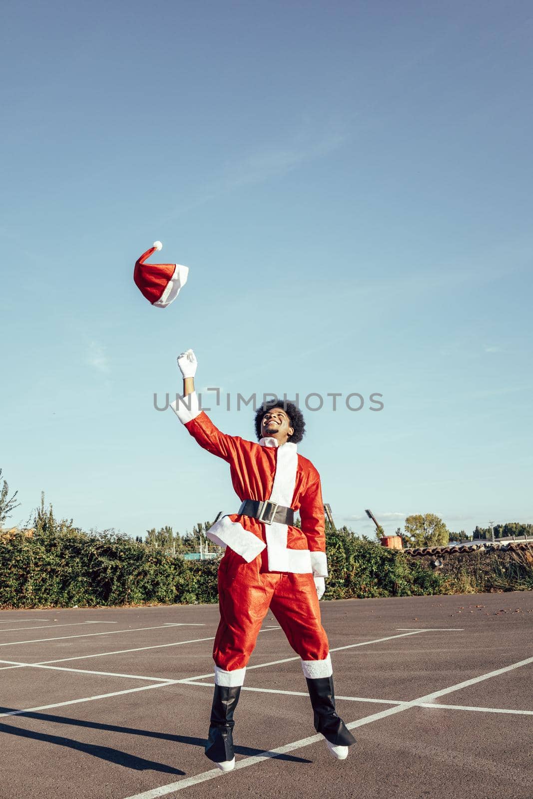 African american santa claus jumping and throwing the hat, vertical copy space