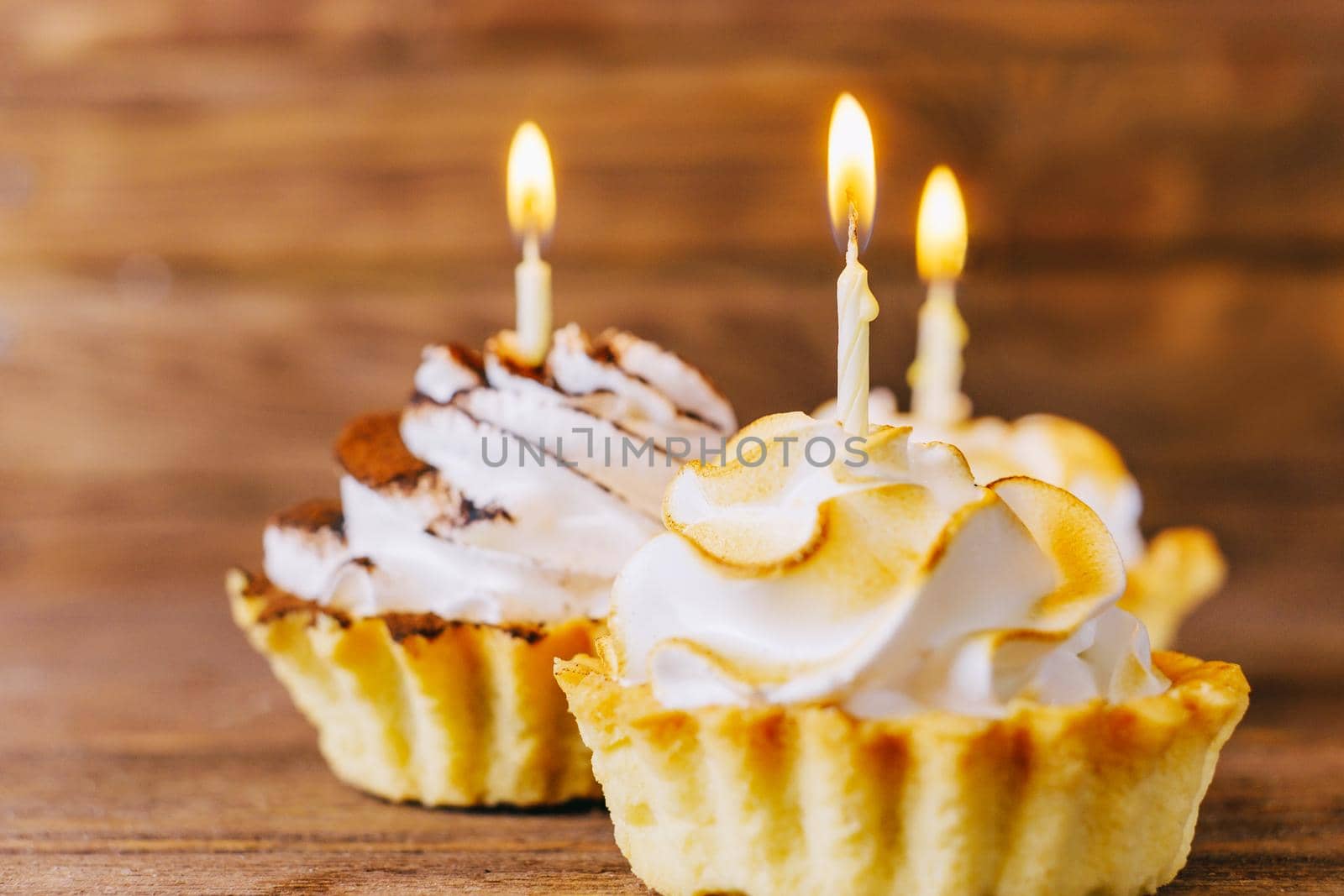 Birthday delicious cupcakes with candles on a wooden table, closeup.