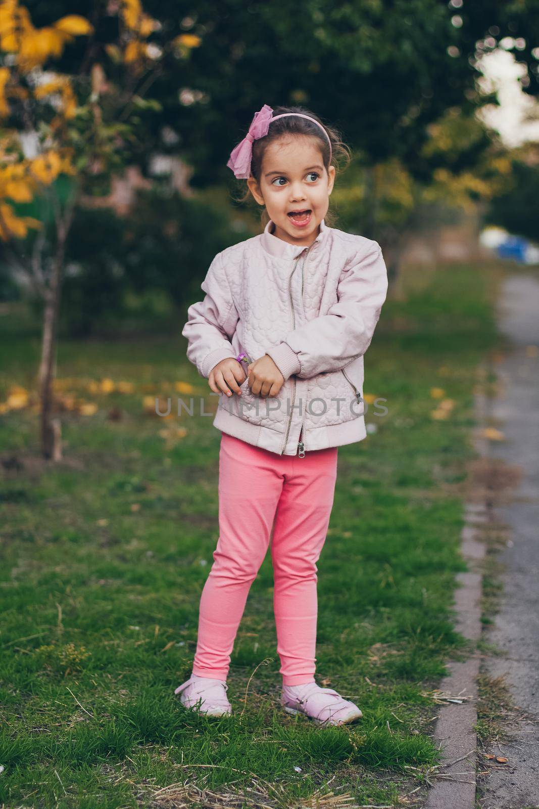 Young girl in a pink jacket and pink leggings in the park.