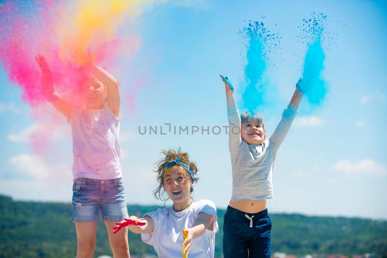 Excited children painted in the colors of Holi festival. Kids splashing colorful paint. by Tverdokhlib