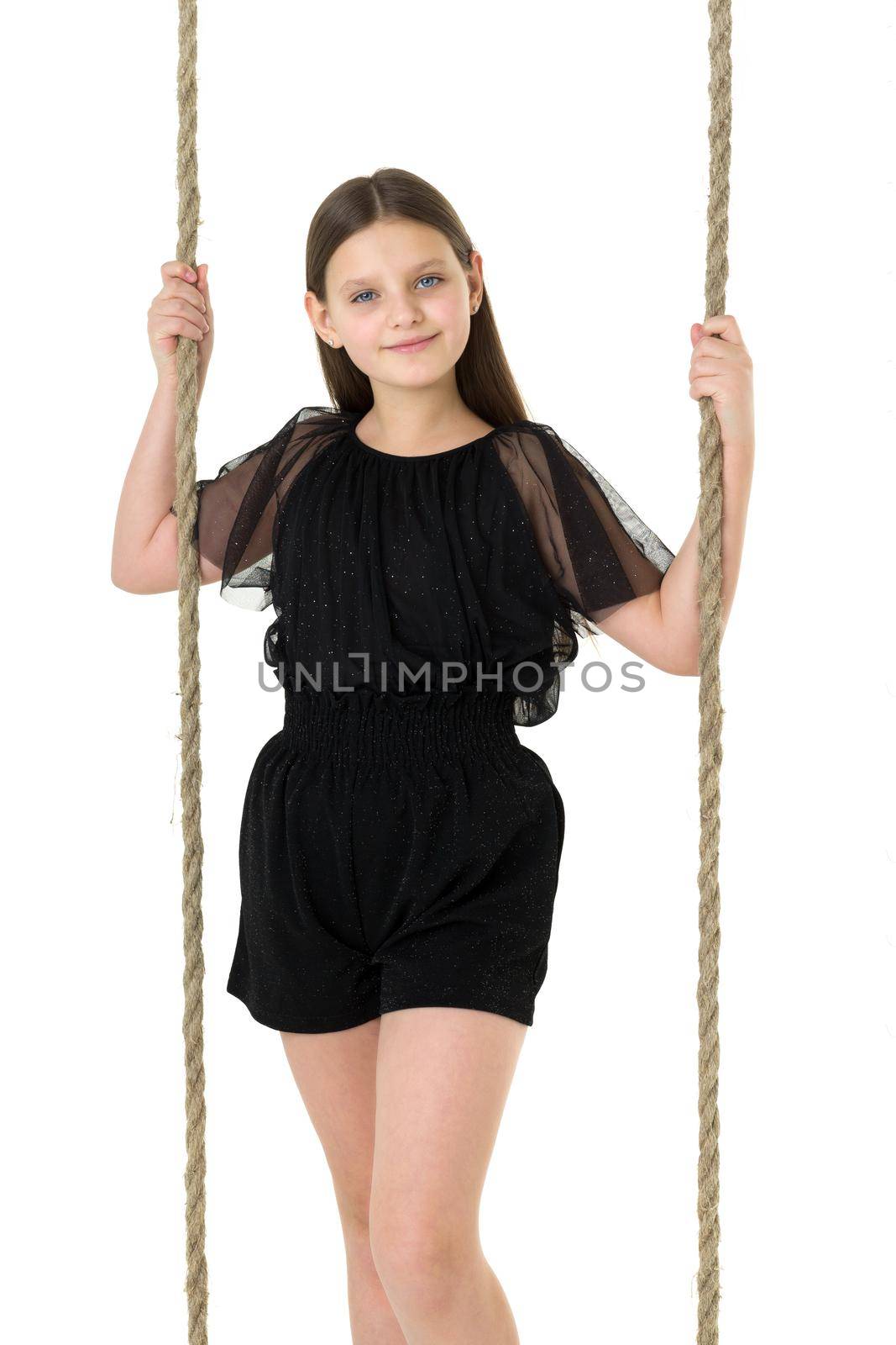 Joyful girl swinging on rope swing. In Stylish Jumpsuit