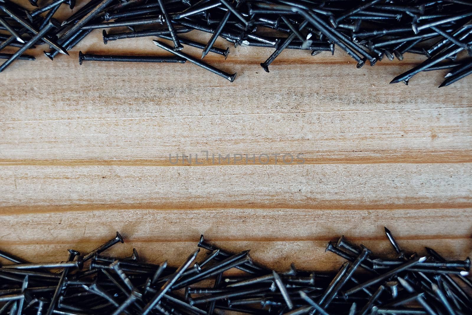 Small nails are scattered on the wooden Board. Background with space to copy. by SergeyPakulin