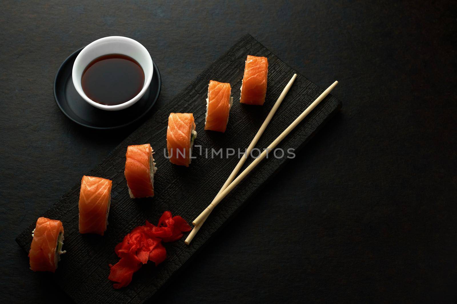 Sushi rolls. Dark style. Serving a meal at a Japanese restaurant. Top view with space to copy. Minimalism in marketing.