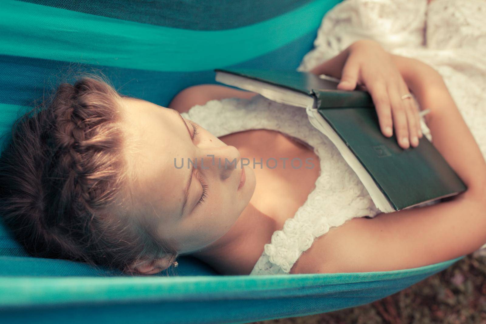 Romantic teenage girl lays on hammock with book of memories