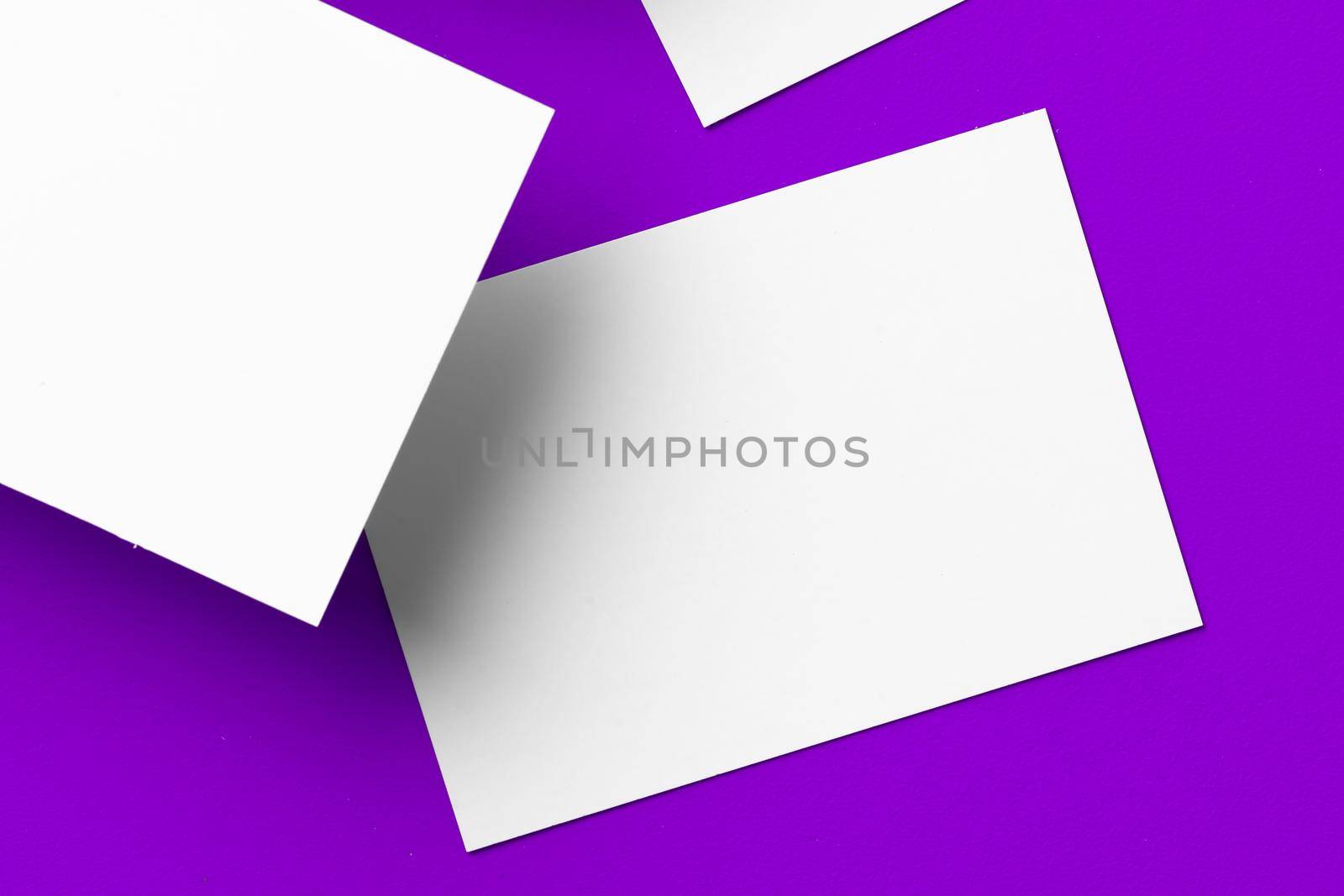 Blank white businesscards on purple background close up, copy space