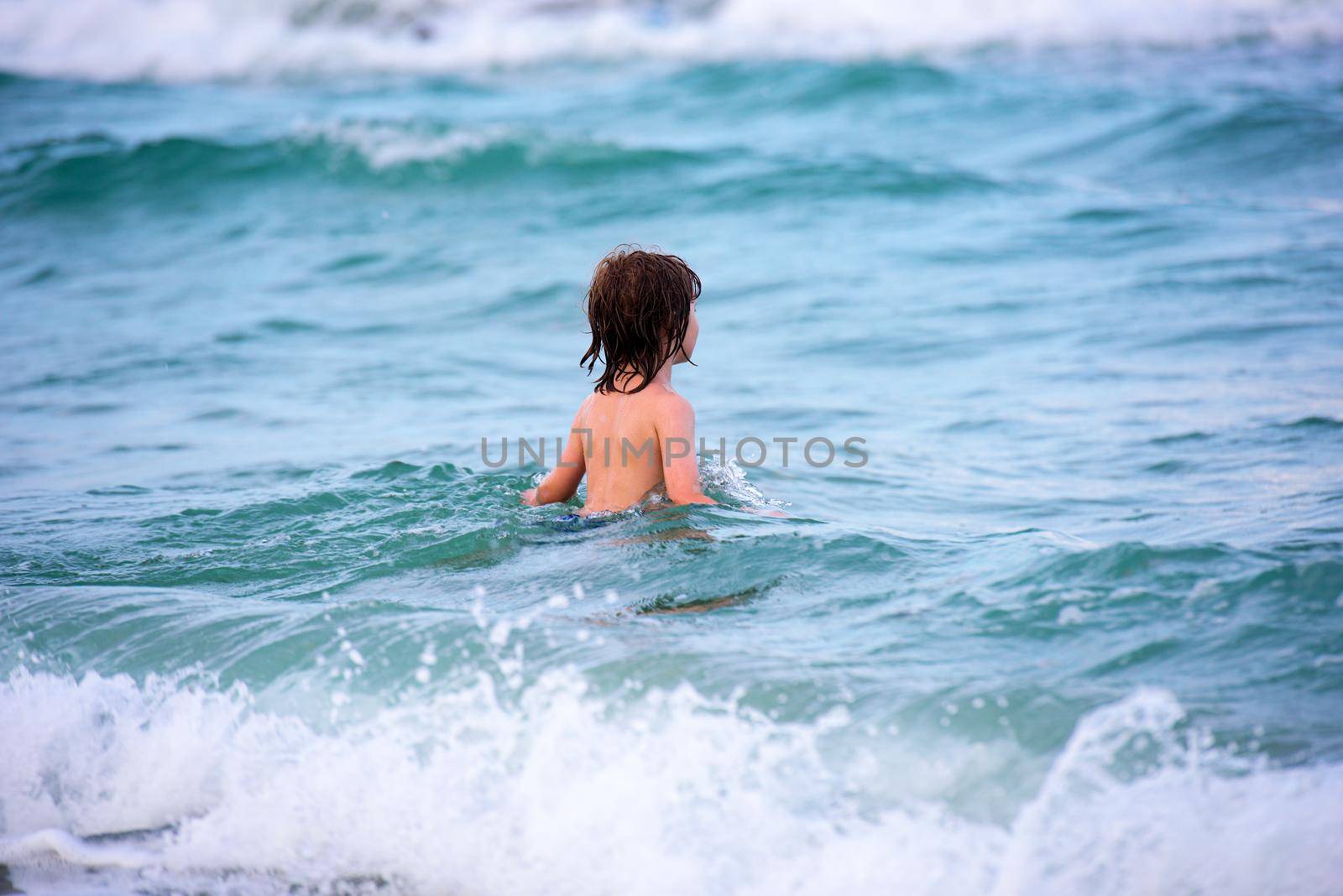 Little boy playing in outdoor jumping into water on summer vacation on tropical beach island