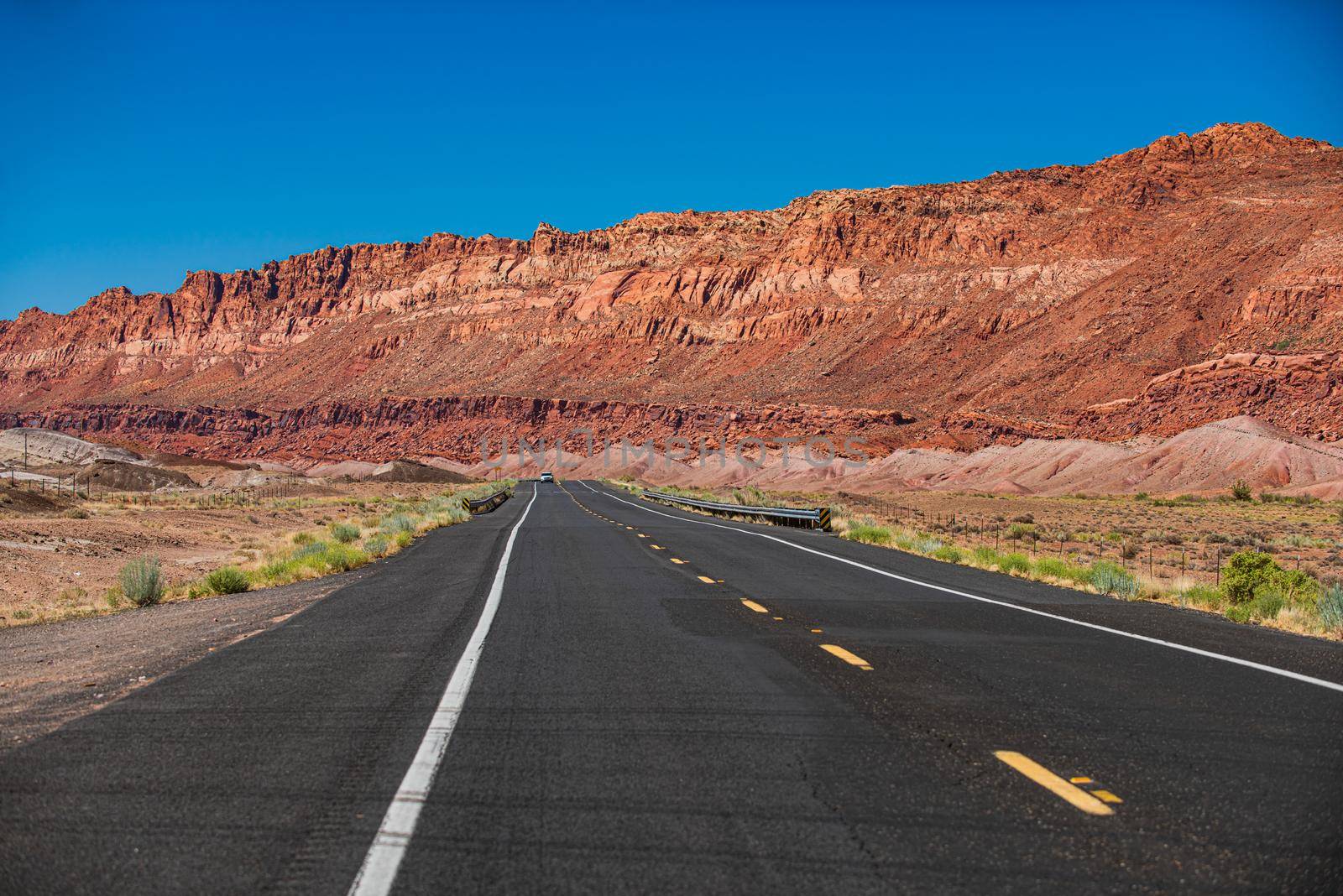 Landscape with rocks, sunny sky with clouds and beautiful asphalt road in the evening in summer. American roadtrip. by Tverdokhlib