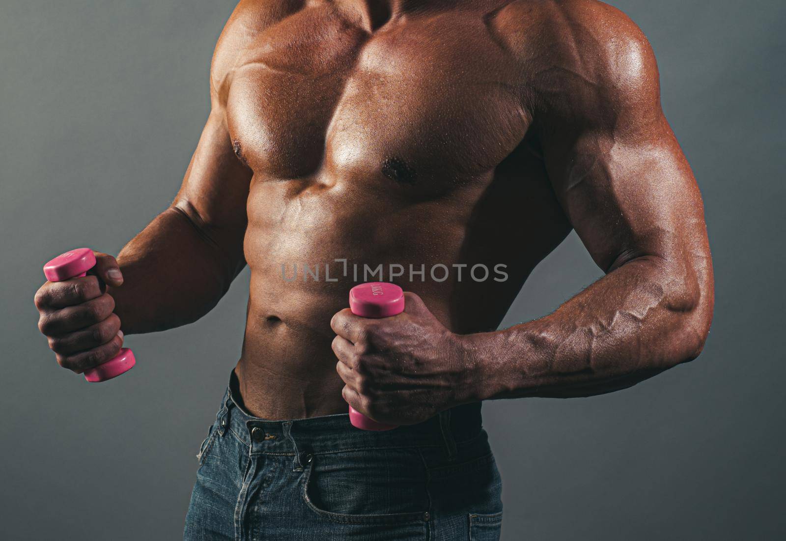 Muscular sexy fitness male body. Man posing shirtless on gray background. Athletic young man with naked torso with dumbbells. Strength and motivation gay concept. Fitness with small dumbbells. by Tverdokhlib