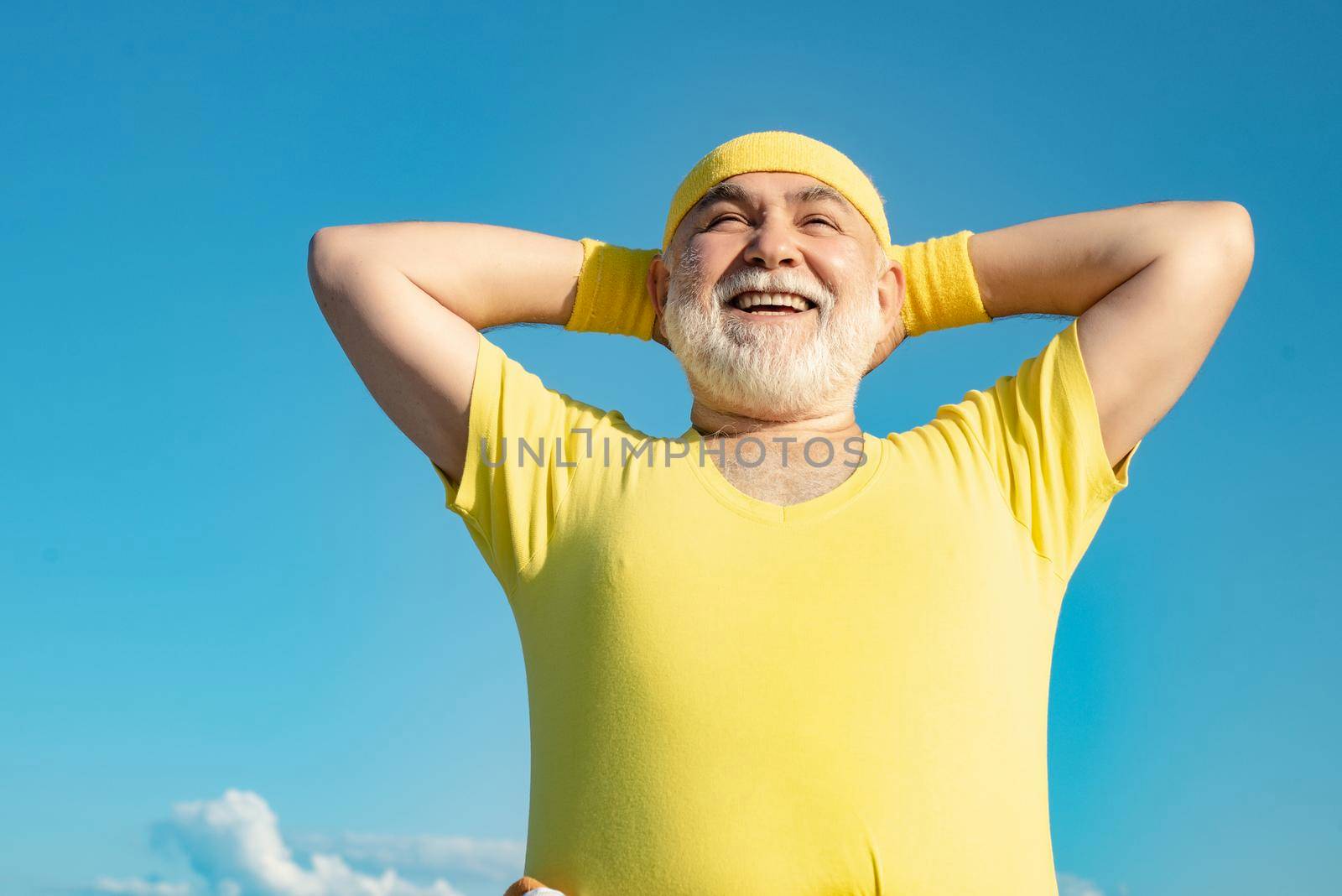 Freedom retirement concept. Elderly man practicing sports on blue sky background. Healthy and sport. Healthcare cheerful lifestyle