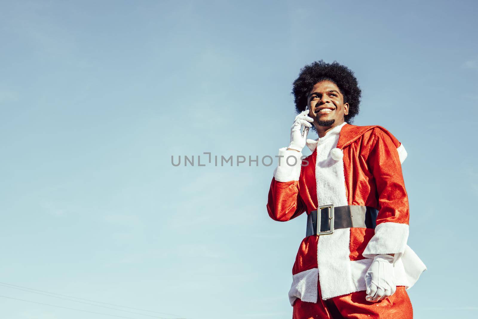 Smiling young african american santa claus talking on the phone